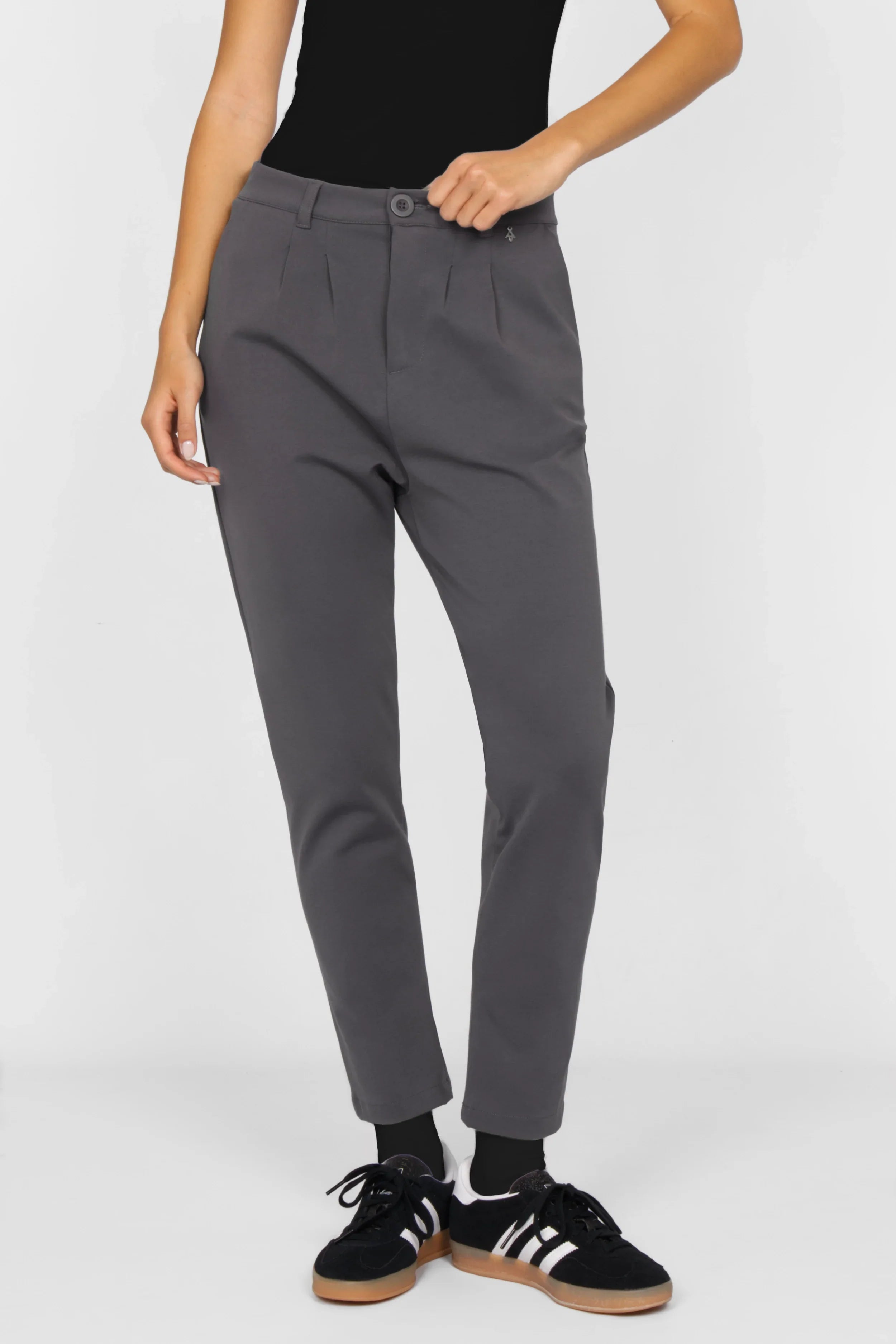 Gray HEELENA tapered pants with soft fabric and a modern, slim fit worn with black sneakers.