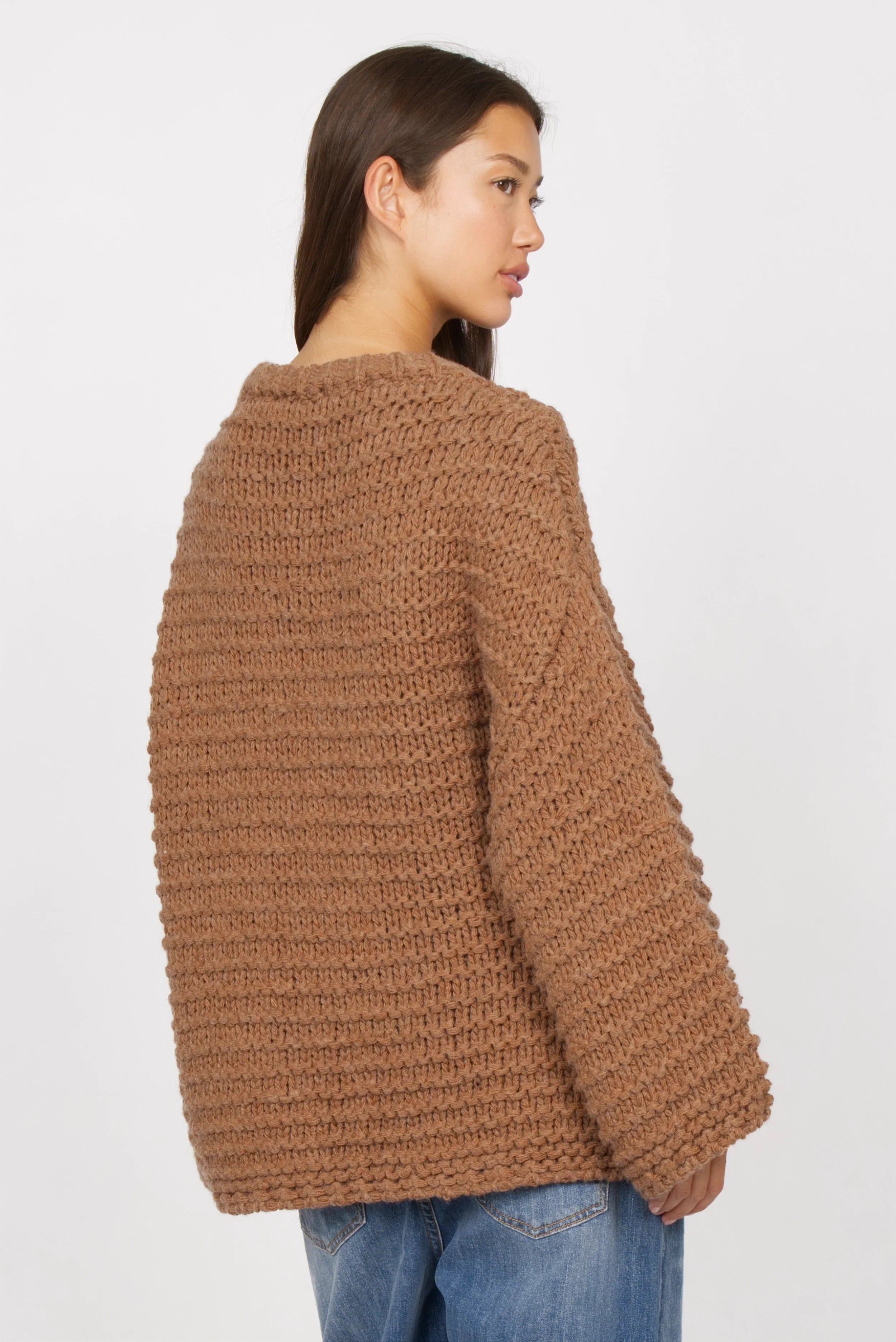 Frau trägt braunen VAILE Oversized Grobstrick Pullover mit kastiger Form und weitem Schnitt von hinten