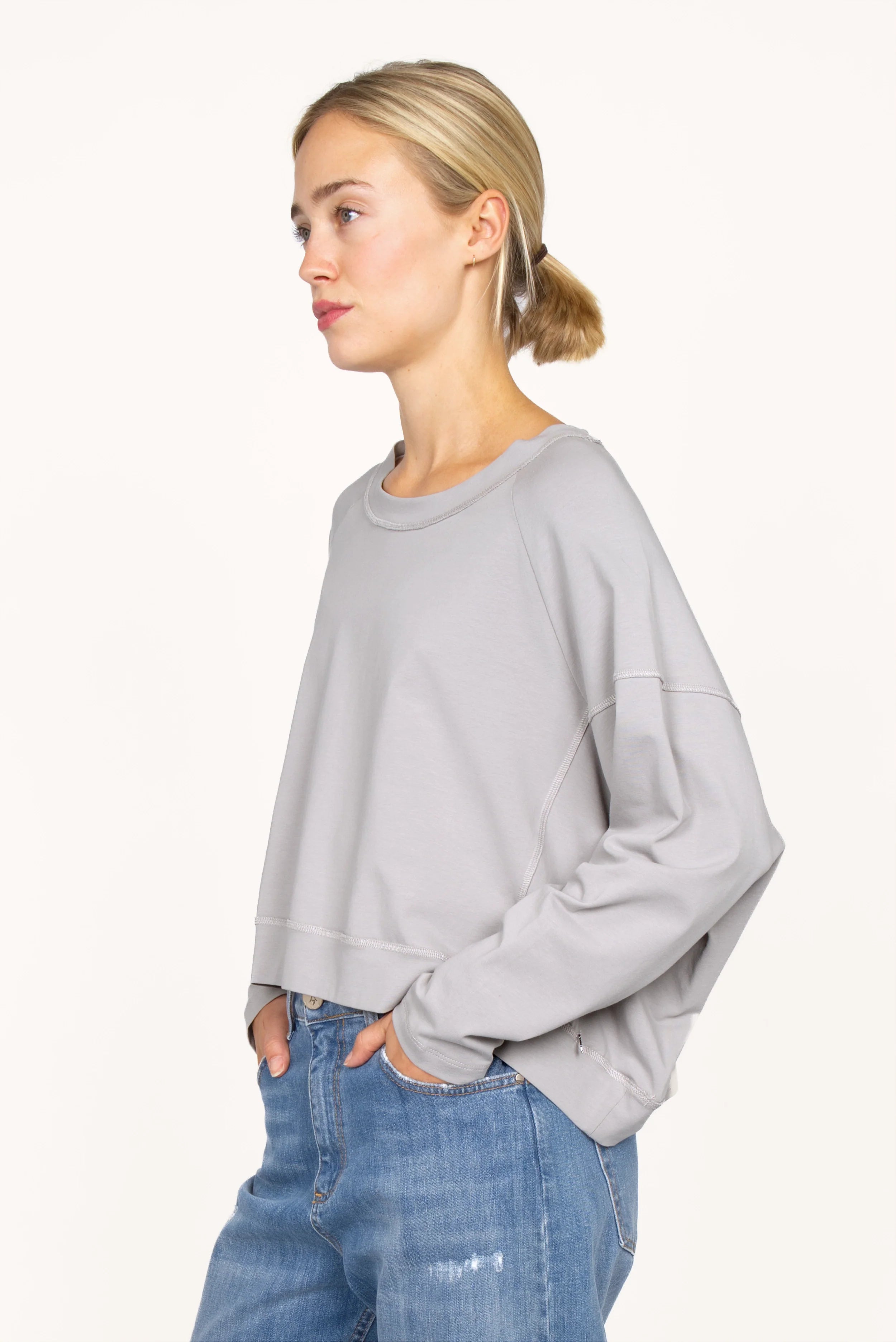 OSASU Cropped Longsleeve in heller Farbe mit weitem Rundhalsausschnitt und lockerer Kastenform, getragen von Frau in Jeans