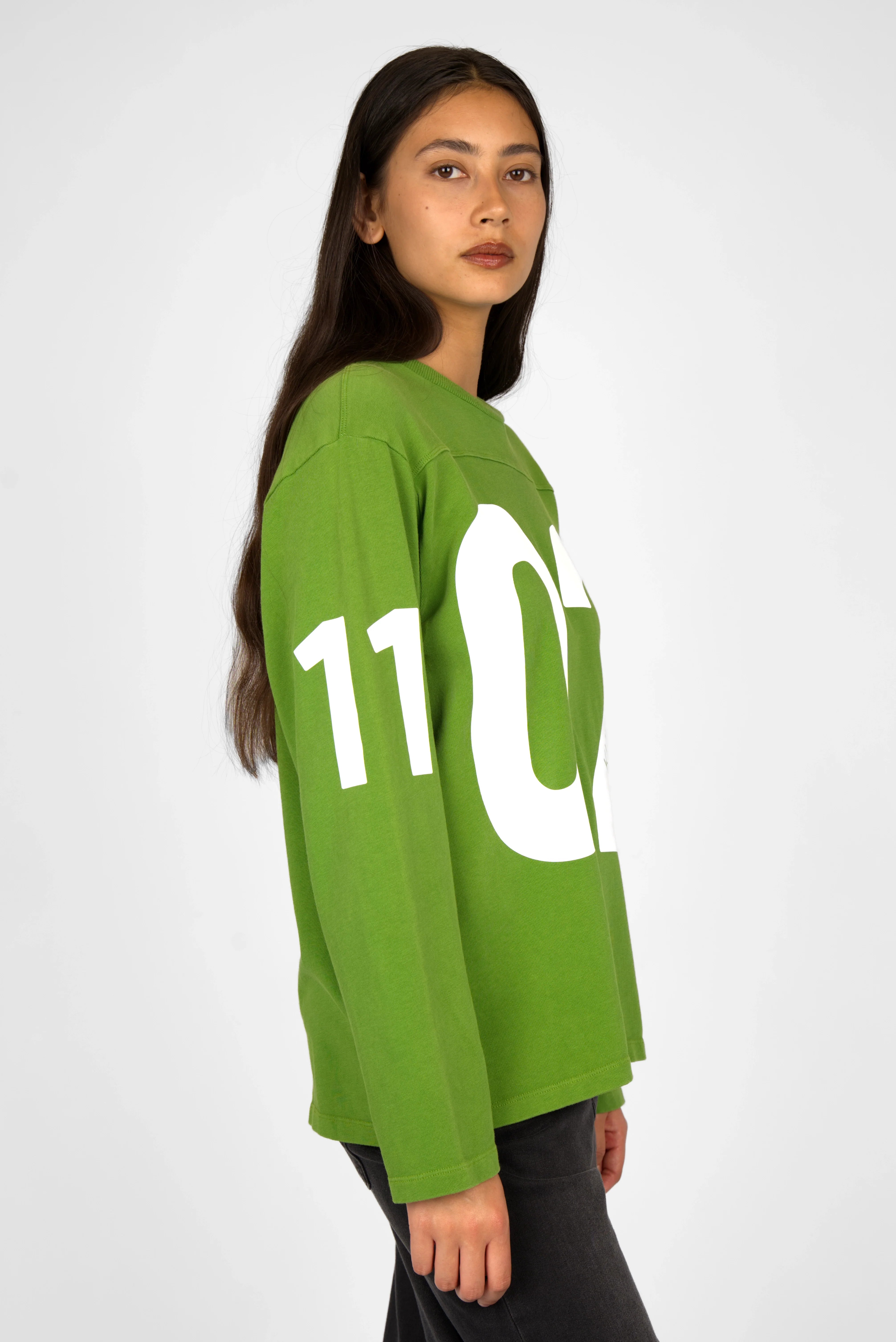 Green AGA Statement Sweater with bold white number print on front and sleeves, worn by model.