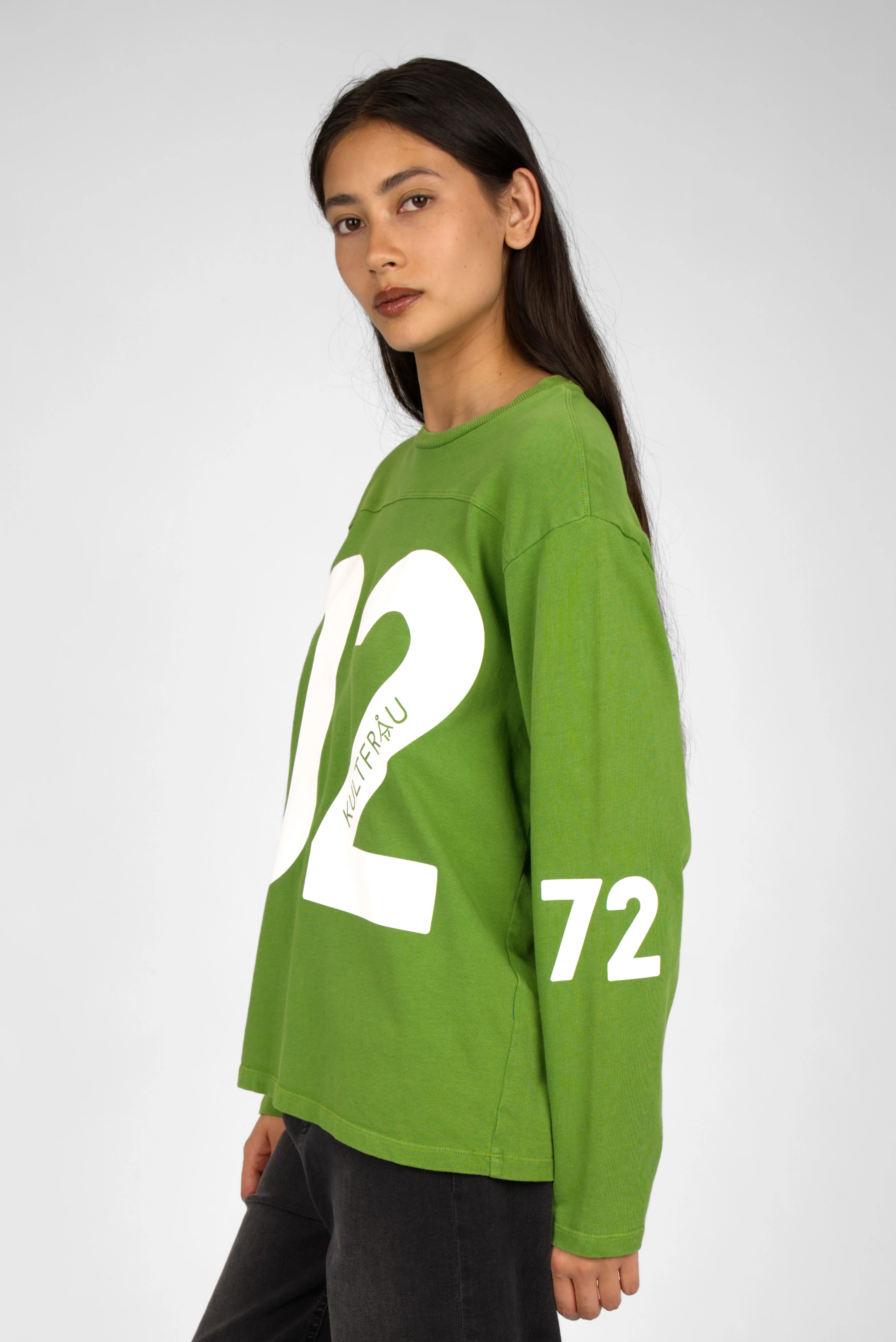 Green AGA Statement Sweater with bold white number print on front and sleeves, worn by female model.