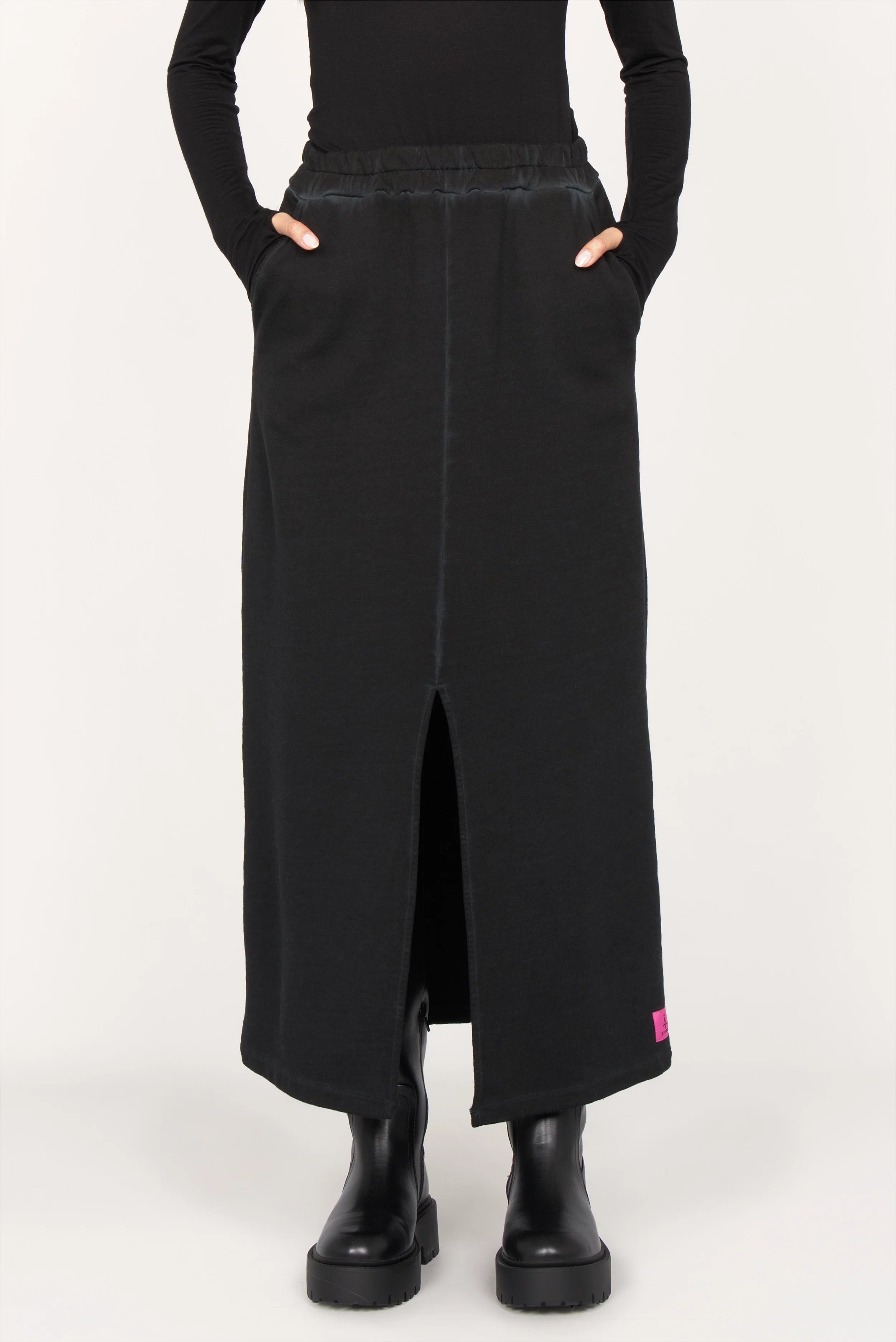 Black ALEMENE Studio Sweatrock midi skirt with front slit, elastic waistband, side pockets, and pink logo patch