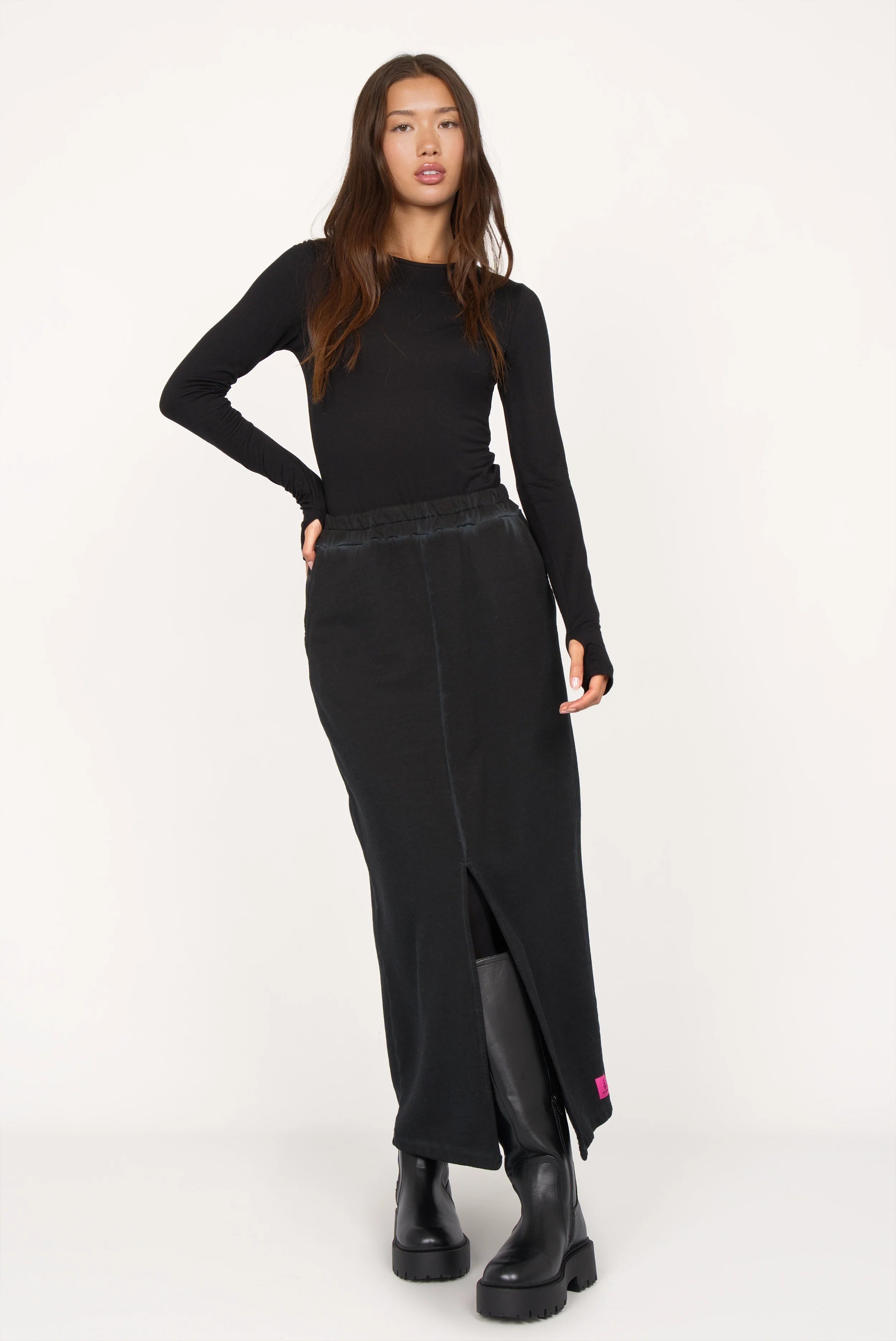 Frau trägt schwarzen ALEMENE Studio Sweatrock mit elastischem Bund und Frontschlitz in Midi-Länge