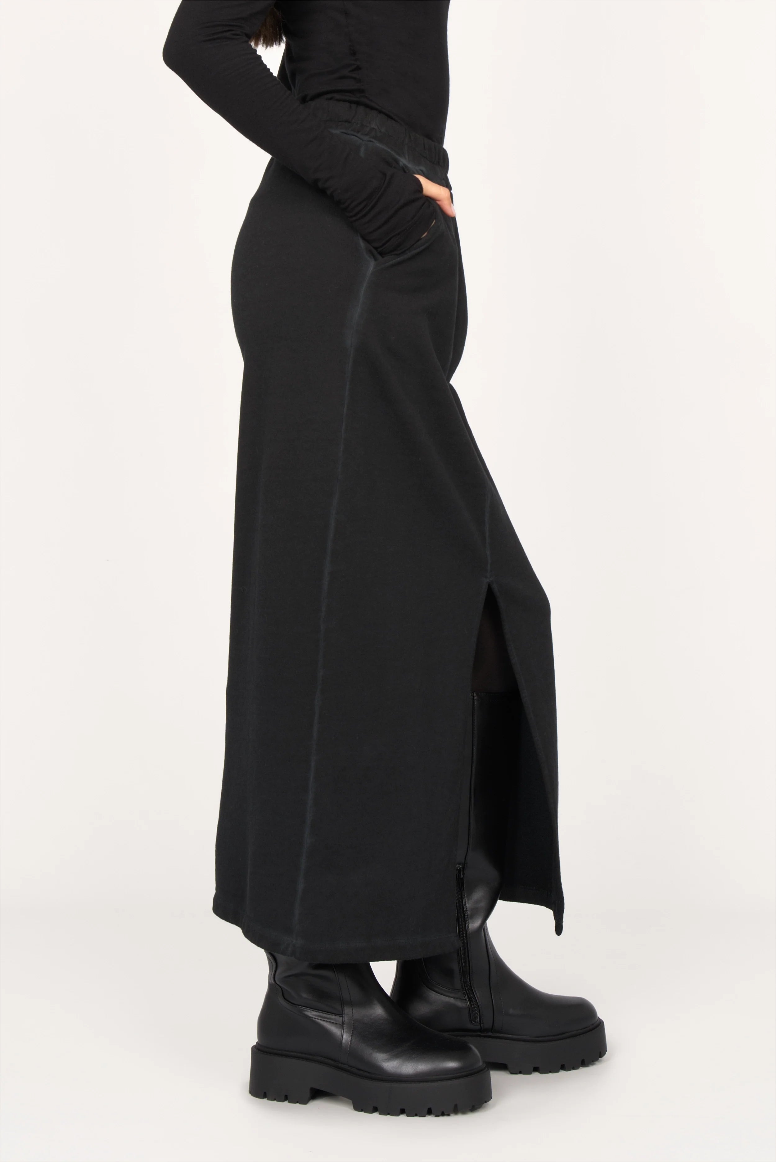 Side view of ALEMENE Studio Sweatrock midi skirt in black cotton sweat with front slit and elastic waistband