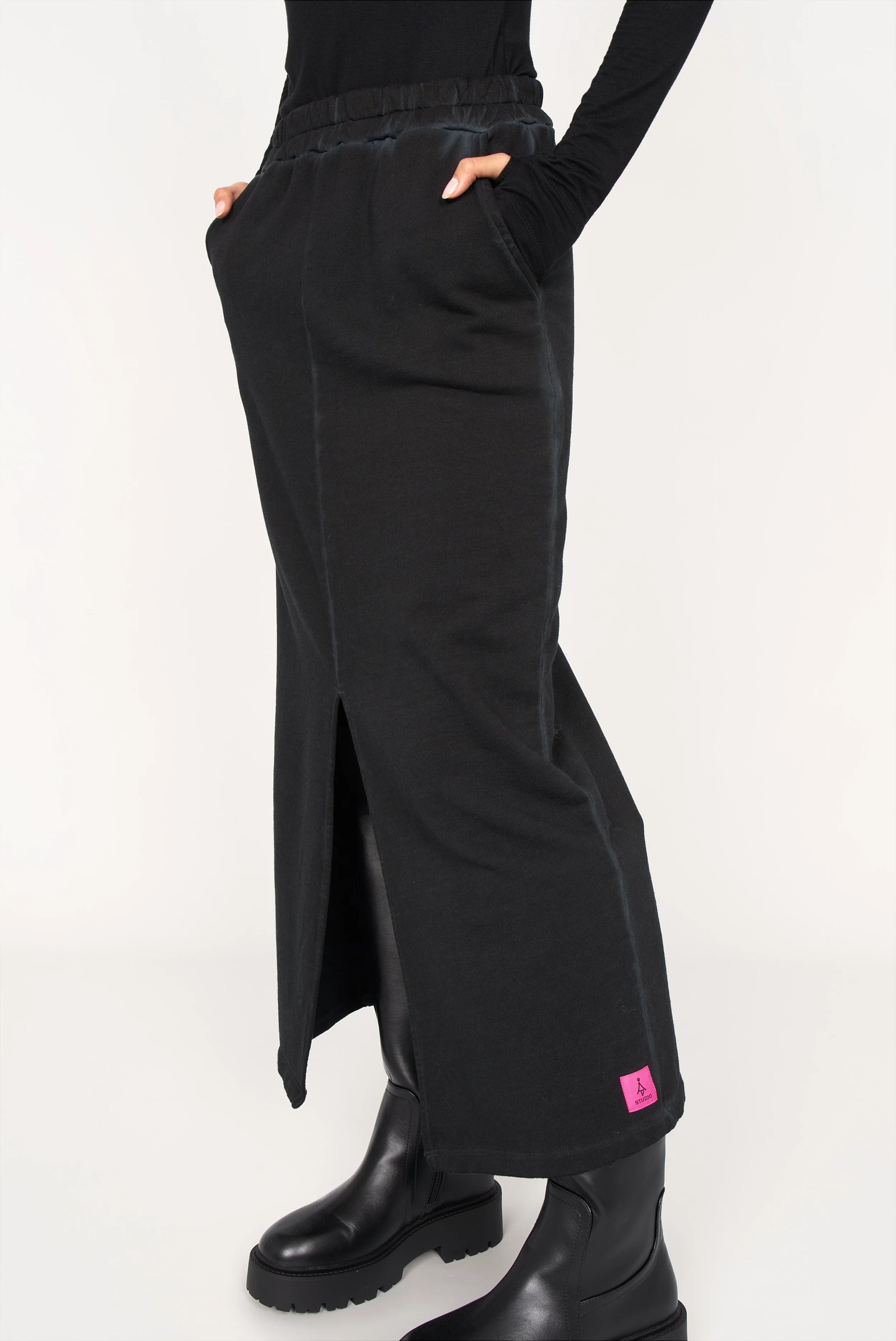 Black ALEMENE Studio Sweatrock midi skirt with elastic waistband, front slit, side pockets, and pink logo patch