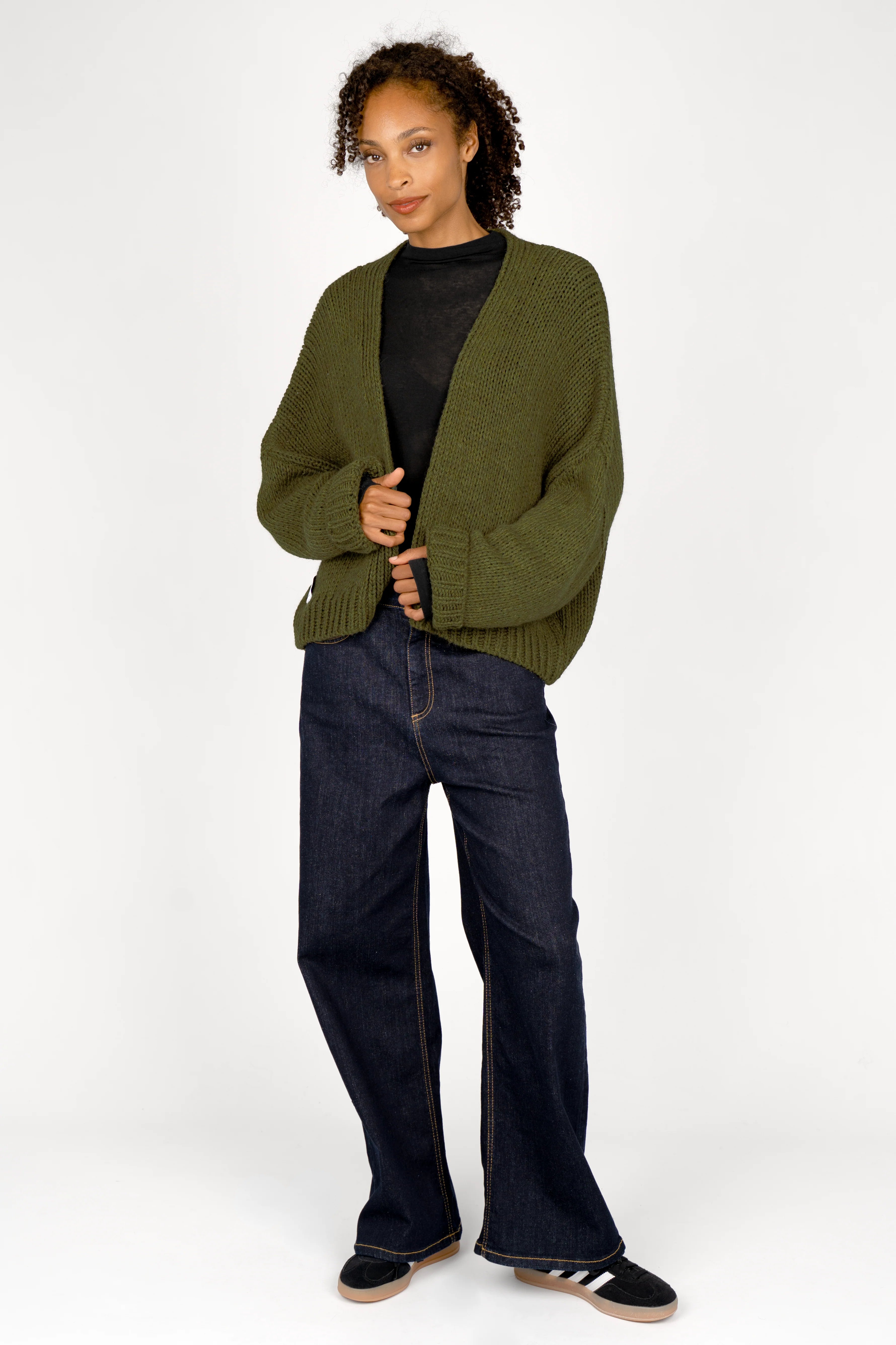 Damenmodell trägt ALIXA Cropped Strickcardigan mit Schalkragen in Olivgrün, oversized, mit weitem Schnitt und gerippten Abschlüssen.