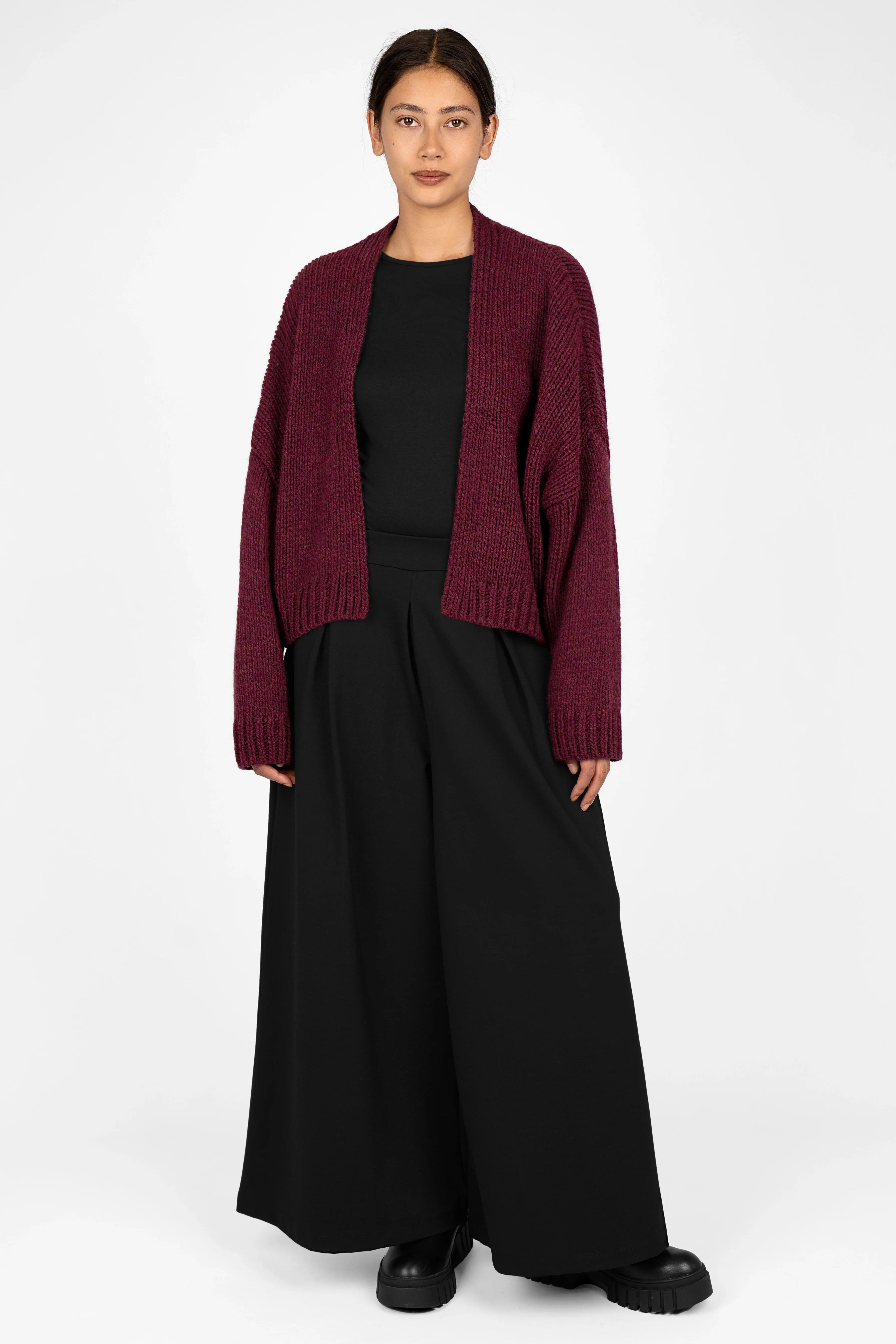 Woman wearing ALIXA Cropped Strickcardigan in burgundy with loose fit and ribbed cuffs over black outfit