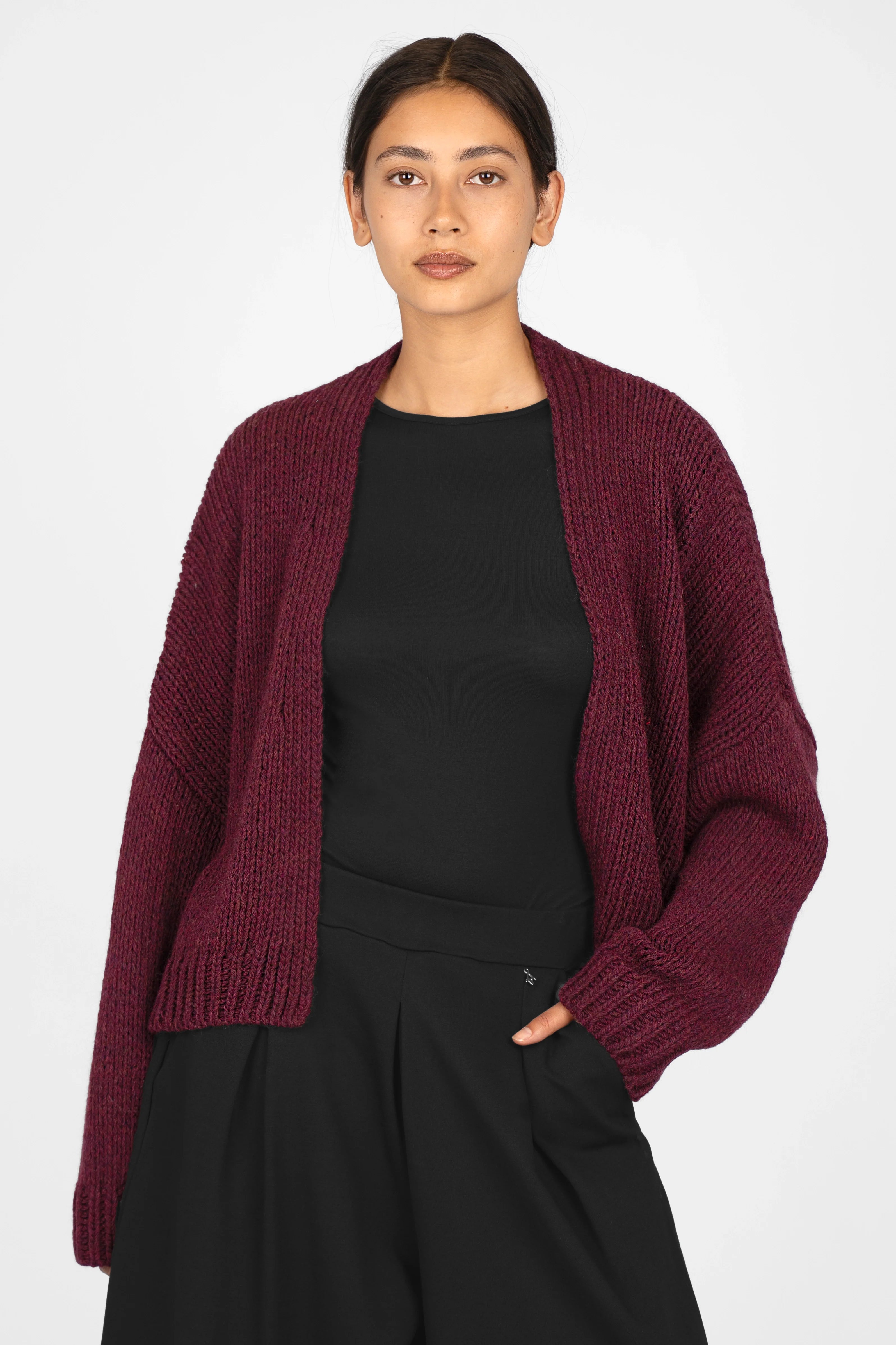 ALIXA Cropped Strickcardigan in deep burgundy with oversized fit, ribbed cuffs, shawl collar, and open front design worn over black top and pants