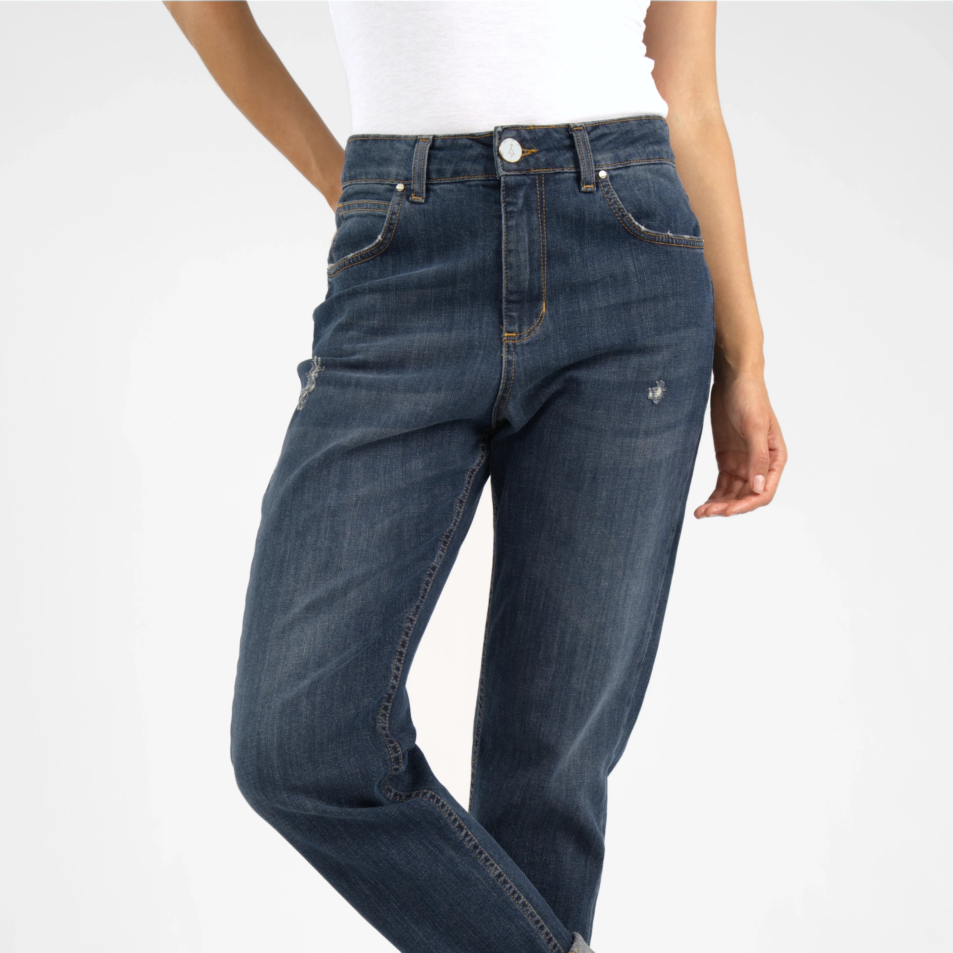 Dark blue mid waist boyfriend jeans with relaxed fit and destroyed details worn rolled up with brown boots