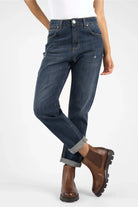 Dark blue mid waist boyfriend jeans with relaxed fit and destroyed details worn rolled up with brown boots
