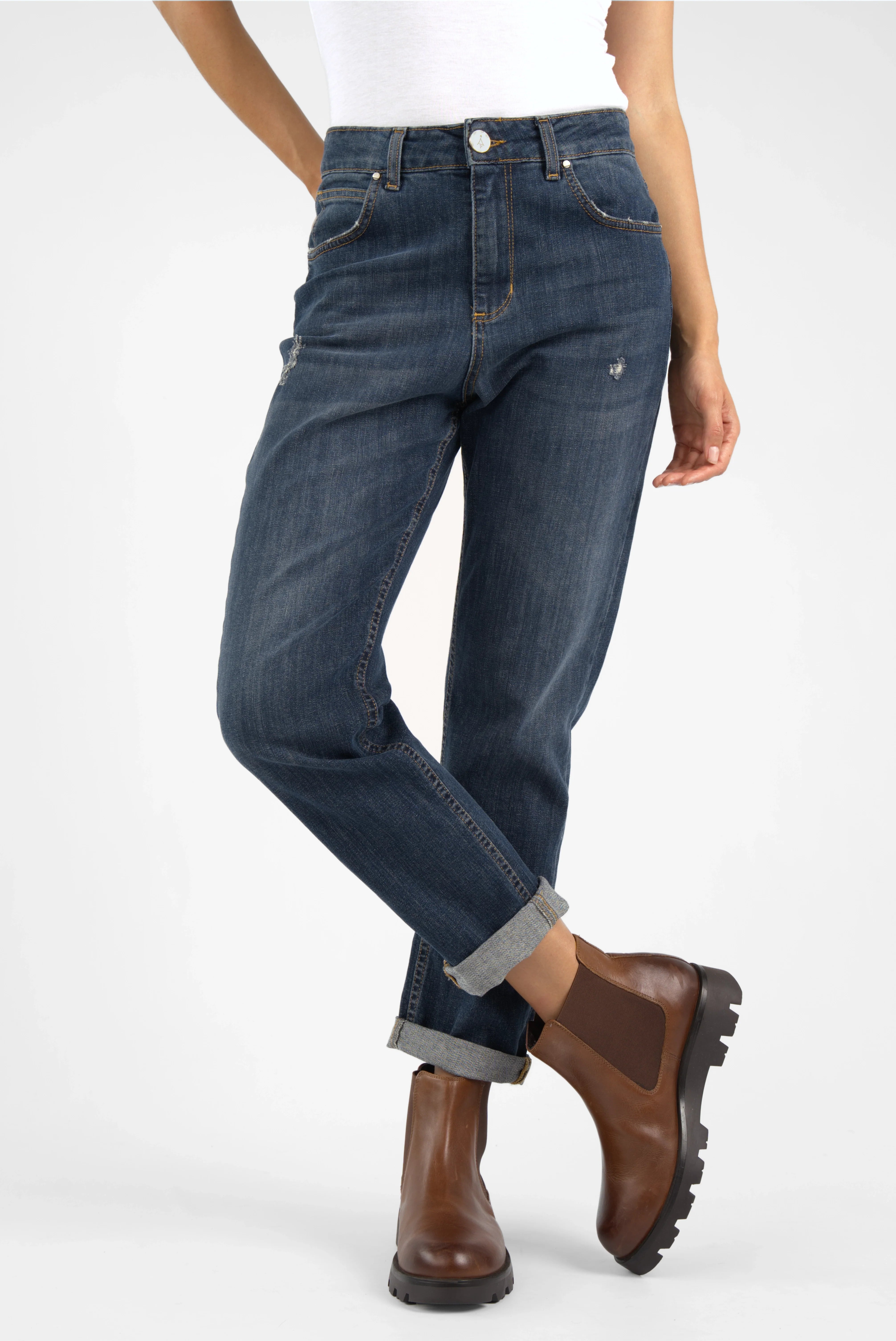 Dark blue mid waist boyfriend jeans with relaxed fit and destroyed details worn rolled up with brown boots