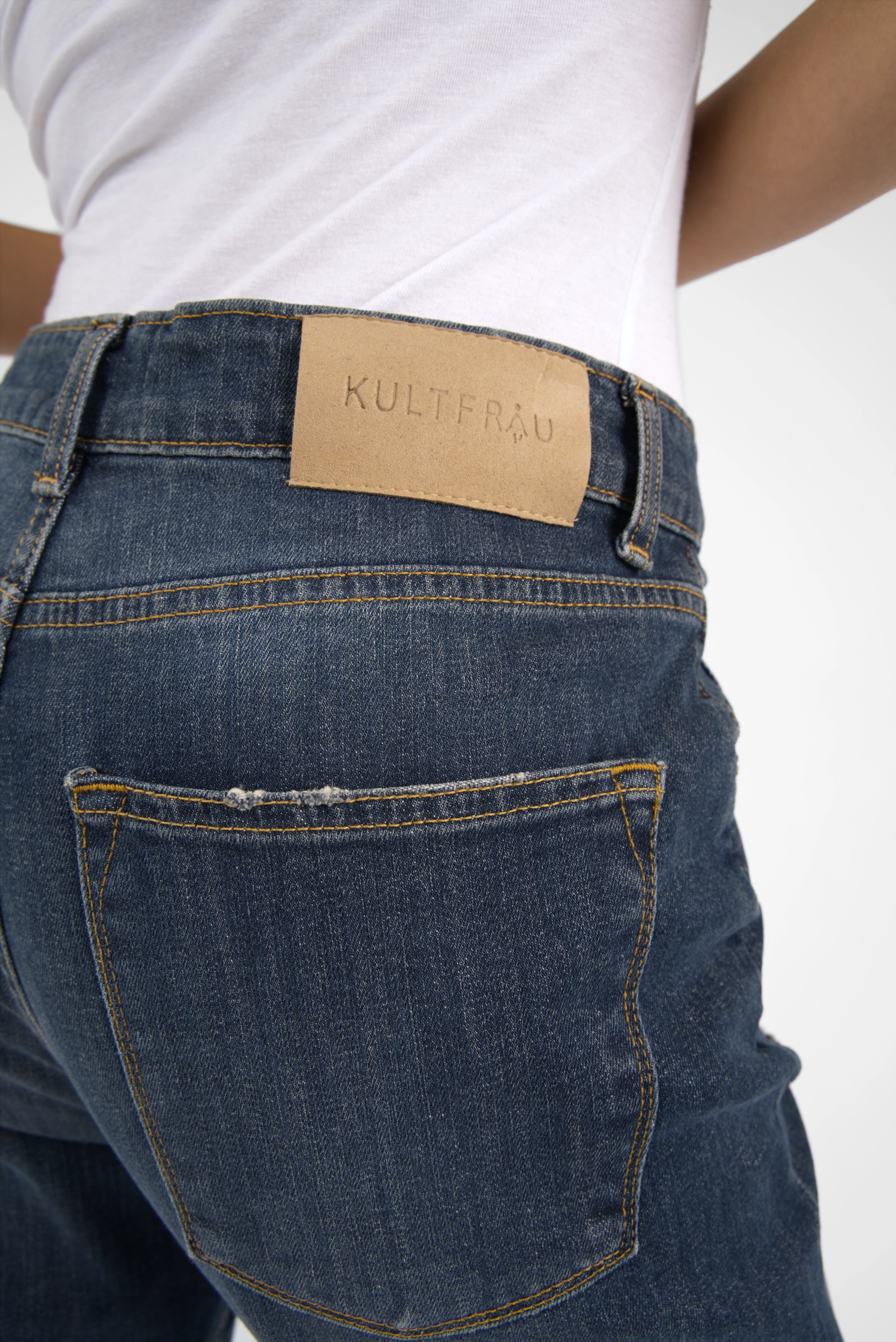 Dark blue boyfriend jeans with mid waist and relaxed fit, featuring destroyed details and a leather brand patch on the back waistband.