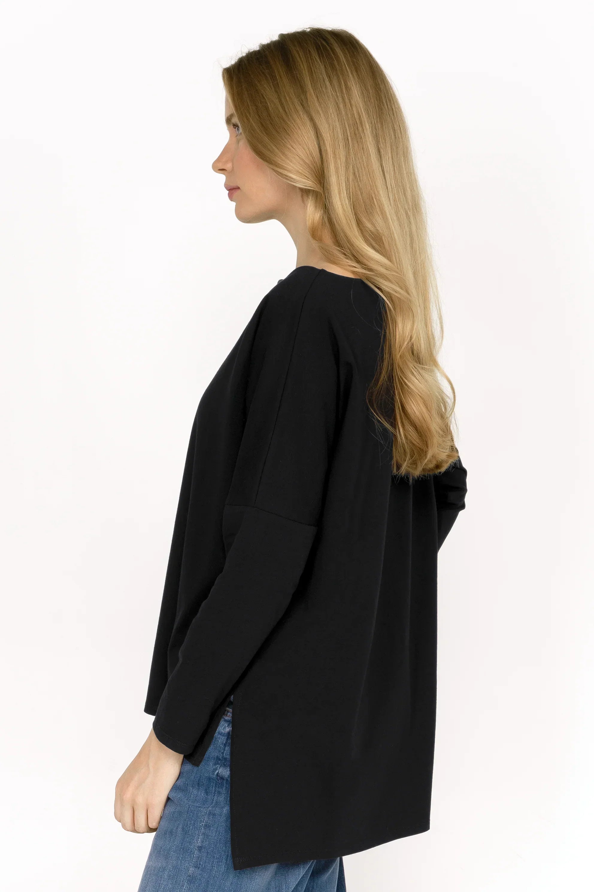 Woman wearing black AMALEA Relaxed Fit longsleeve with boat neckline, dropped shoulders, side slits, and extended back hem