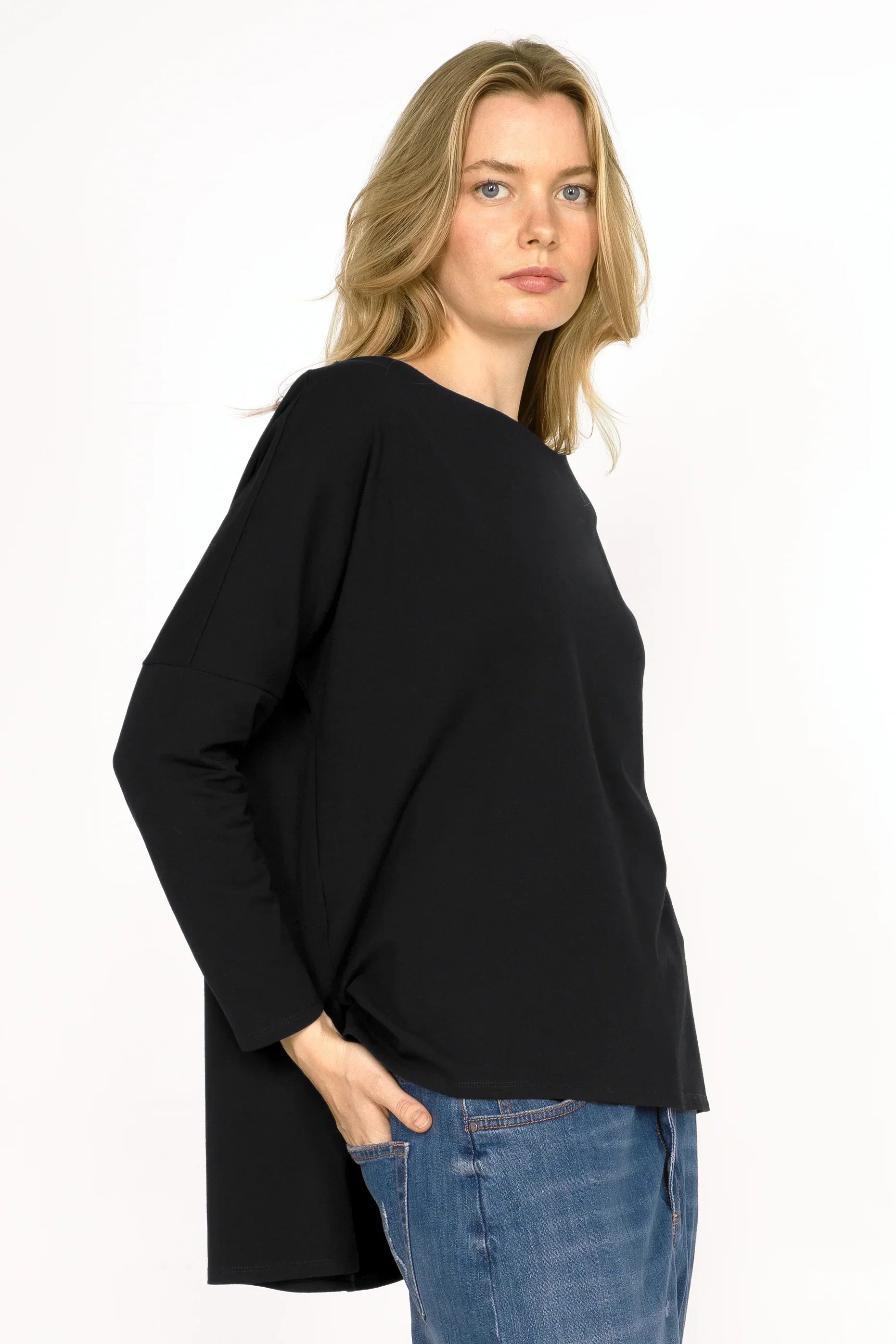 AMALEA Relaxed Fit black long sleeve top with boat neckline, dropped shoulders, side slits, and extended back hem worn by model