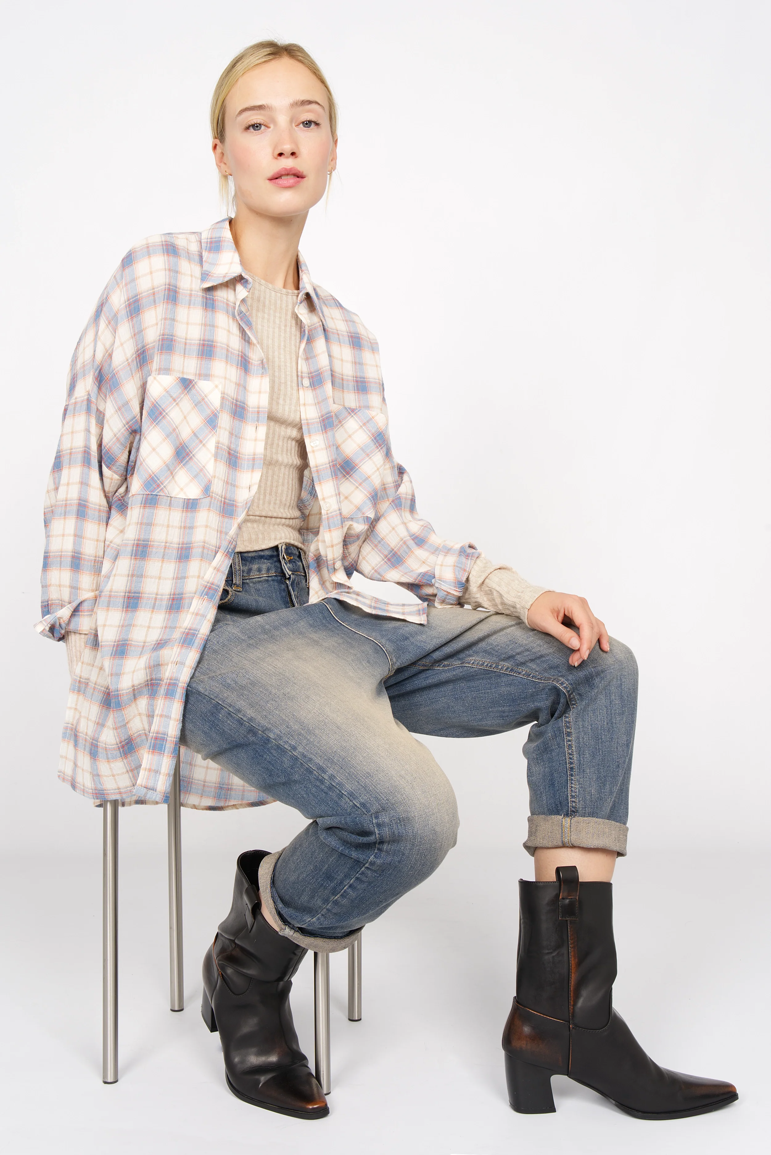 Frau trägt BETTIE Longsleeve aus feinem Rippstrick mit slim Fit, extra langen Ärmeln und Rundhalsausschnitt, kombiniert mit Jeans und Stiefeln.