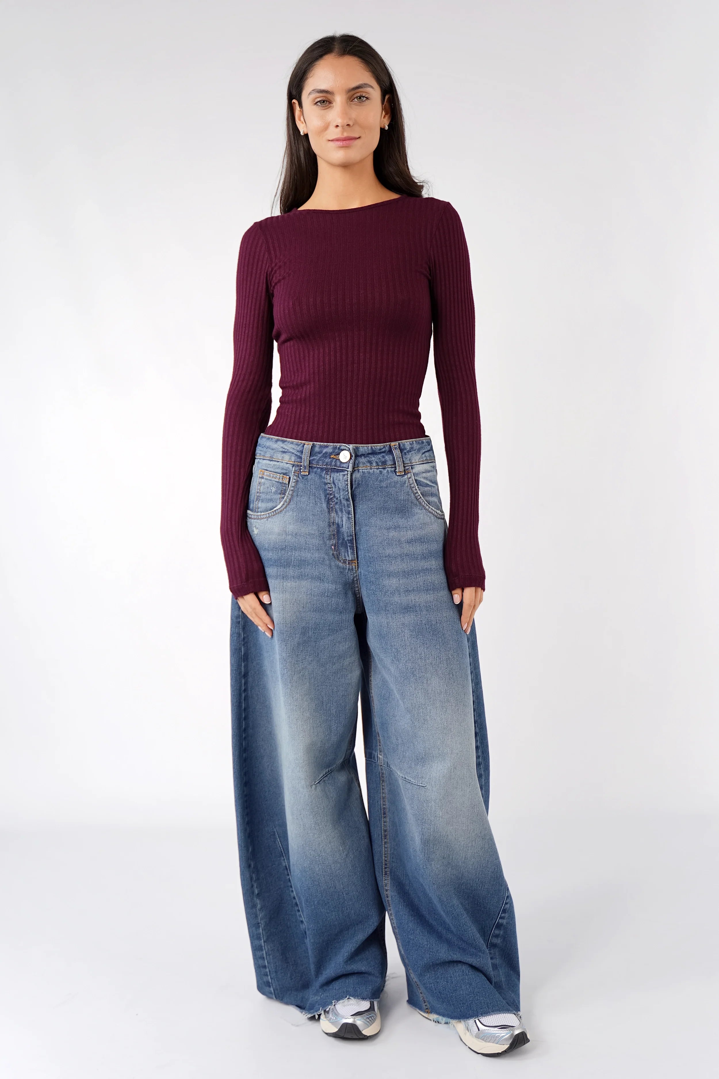 Fitted burgundy Bettie Longsleeve with ribbed texture and extra long sleeves on model wearing wide-leg jeans
