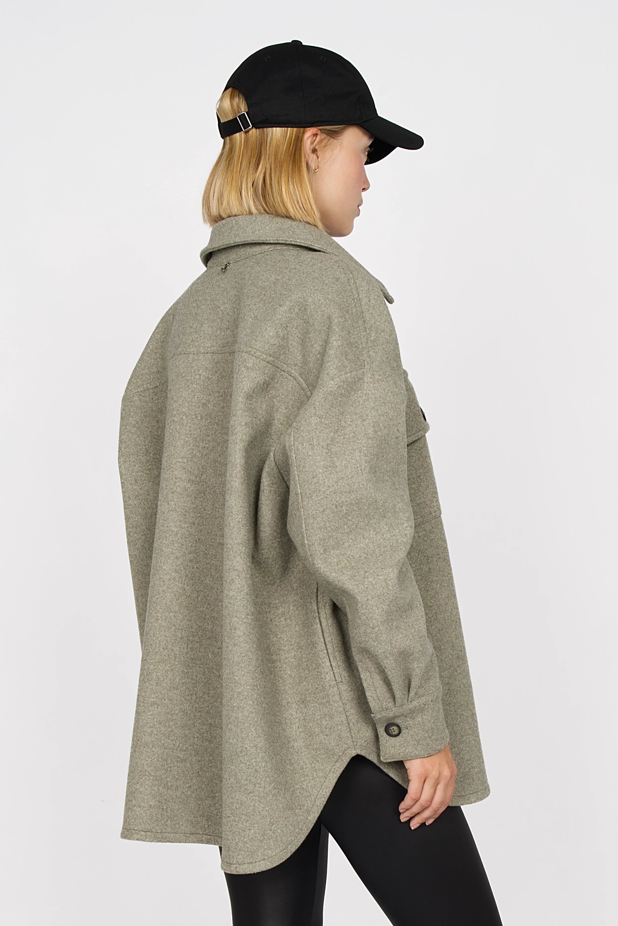 Frau trägt BJORA Overshirt aus festem Wollmix in lockerem, oversized Schnitt mit abgerundetem Saum und Manschettenknöpfen