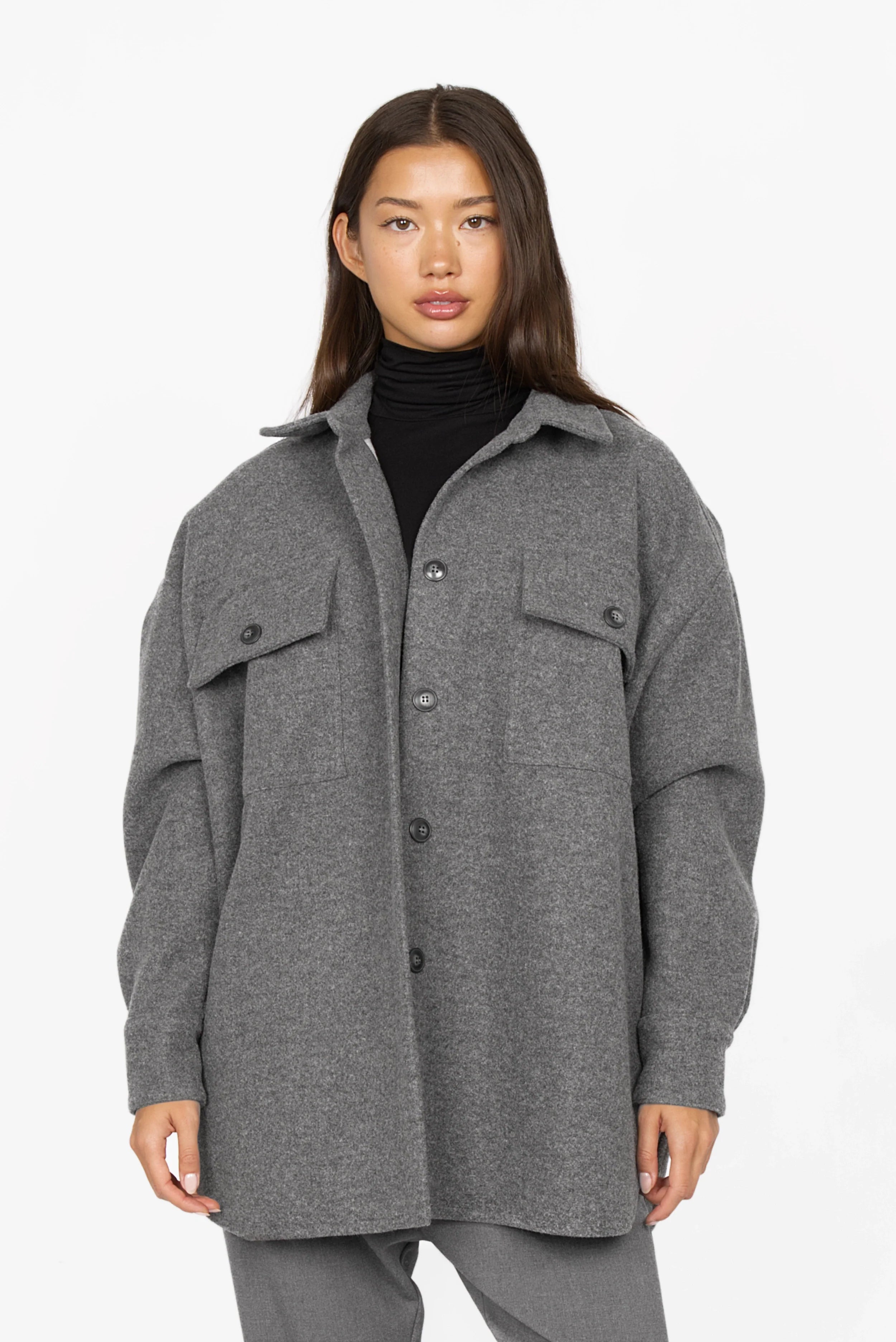 Woman wearing grey BJORA Overshirt wool blend with chest and side pockets, buttoned cuffs, and relaxed fit.