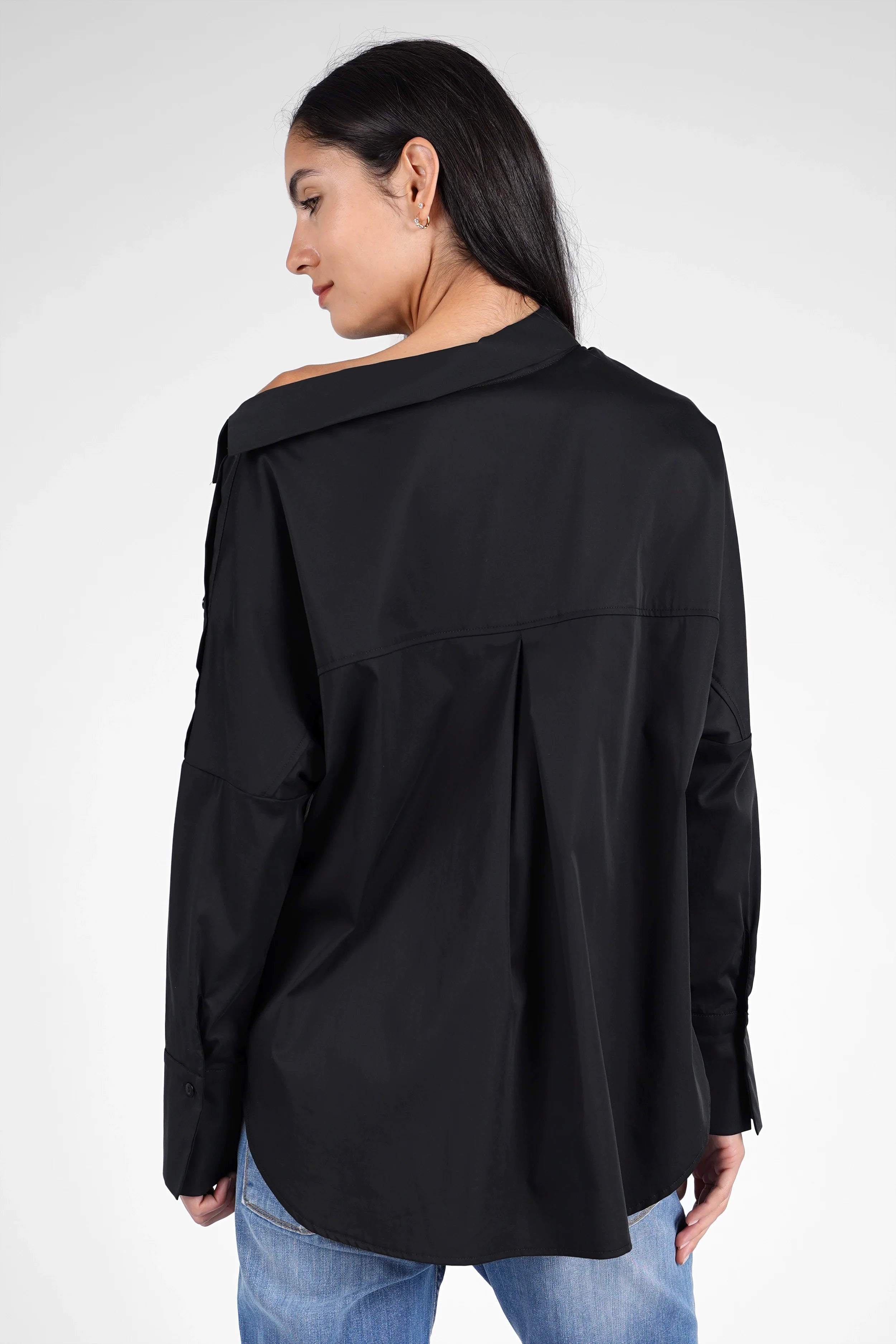 Frau trägt BONI asymmetrische One Shoulder Bluse in Schwarz mit lockerem Schnitt und längerem Rückenteil