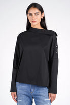 Frau trägt schwarze BONI Asymmetrische One Shoulder Bluse mit Knopfleiste an der Schulter und weitem Manschettenärmel im Relaxed Fit