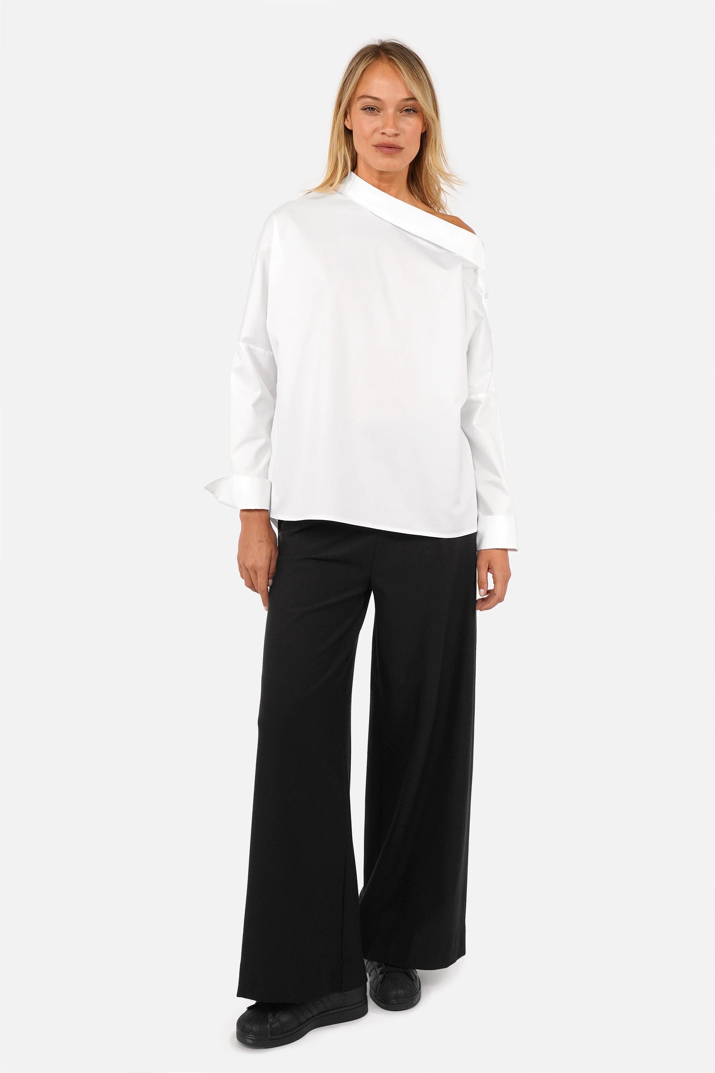 Modisches Model trägt asymmetrische One Shoulder Bluse aus Baumwollmix mit Knopfleiste und breiten Manschetten