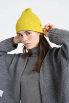 Damen mit gelber gerippter Mütze aus weichem Viskose-Mix und grauem Strickmantel