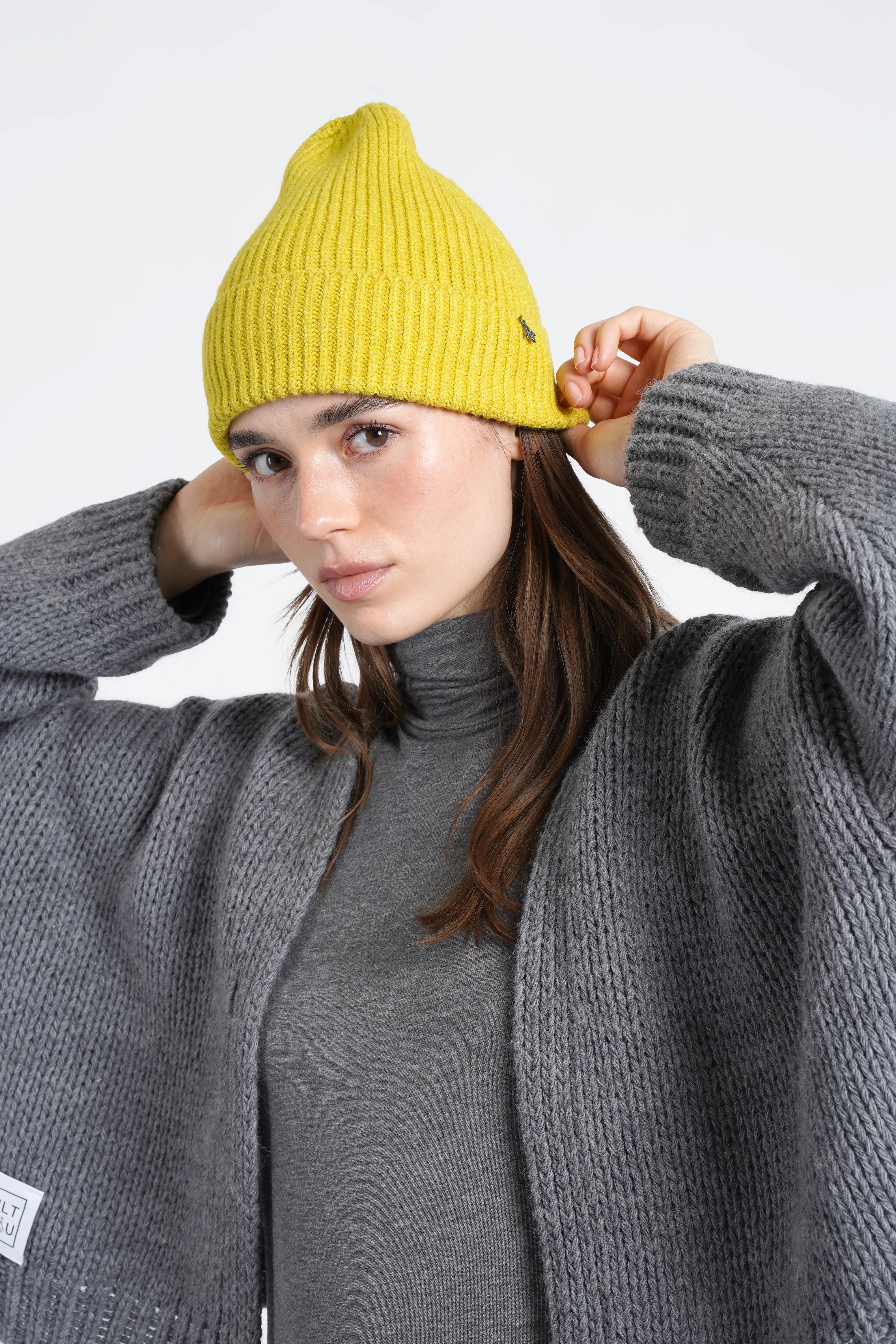 Damen mit gelber gerippter Mütze aus weichem Viskose-Mix und grauem Strickmantel