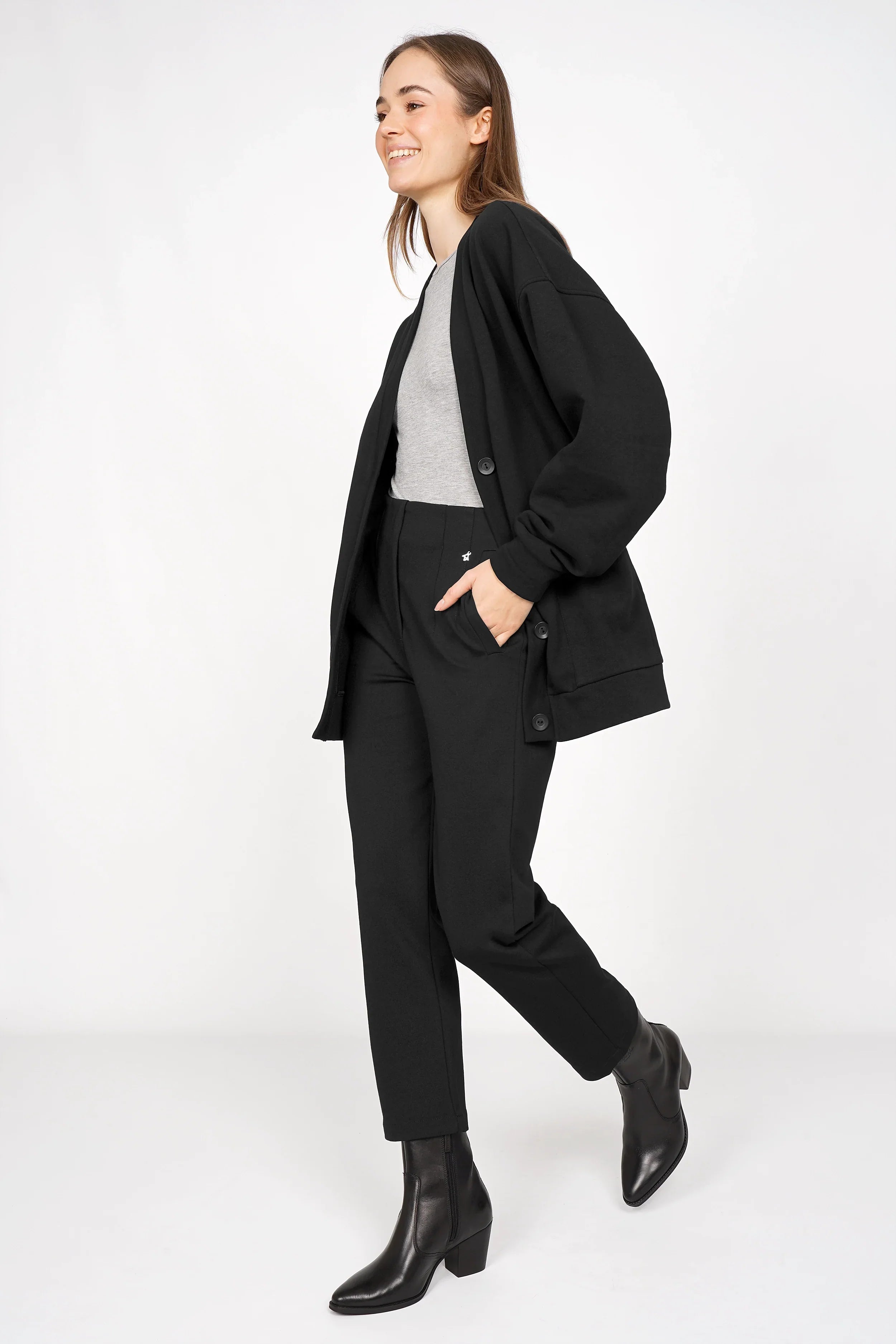 Woman wearing black CEELIA Ankle Pants with cropped slim fit and side pockets, paired with black jacket and boots