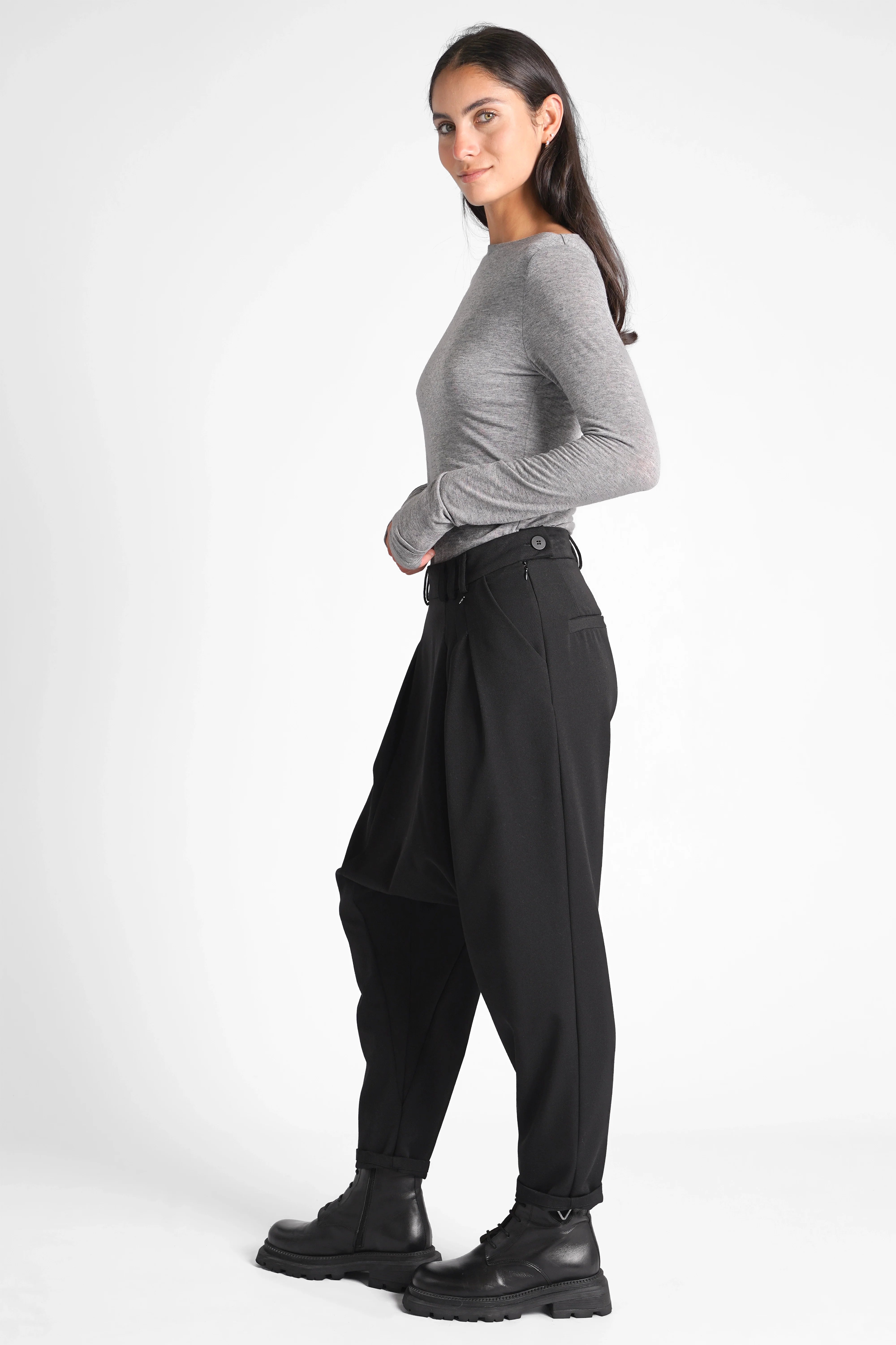 Frau trägt schwarze DEEP Avantgarde-Hose mit extra tiefem Schritt und seitlicher Knopfschließe in Relaxed Fit.