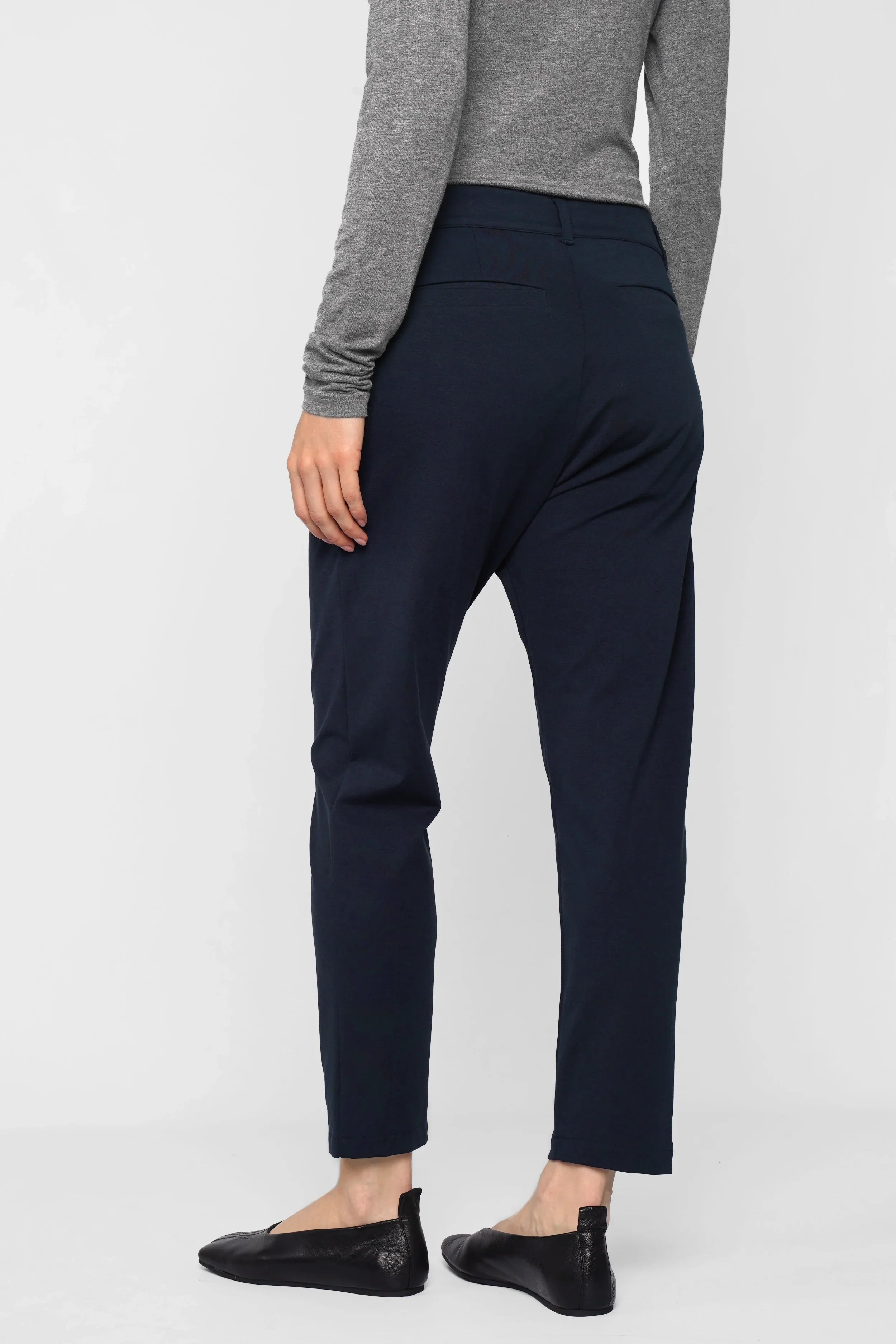 Back view of woman wearing navy HEELENA Tapered Pants with tapered leg and cropped length.