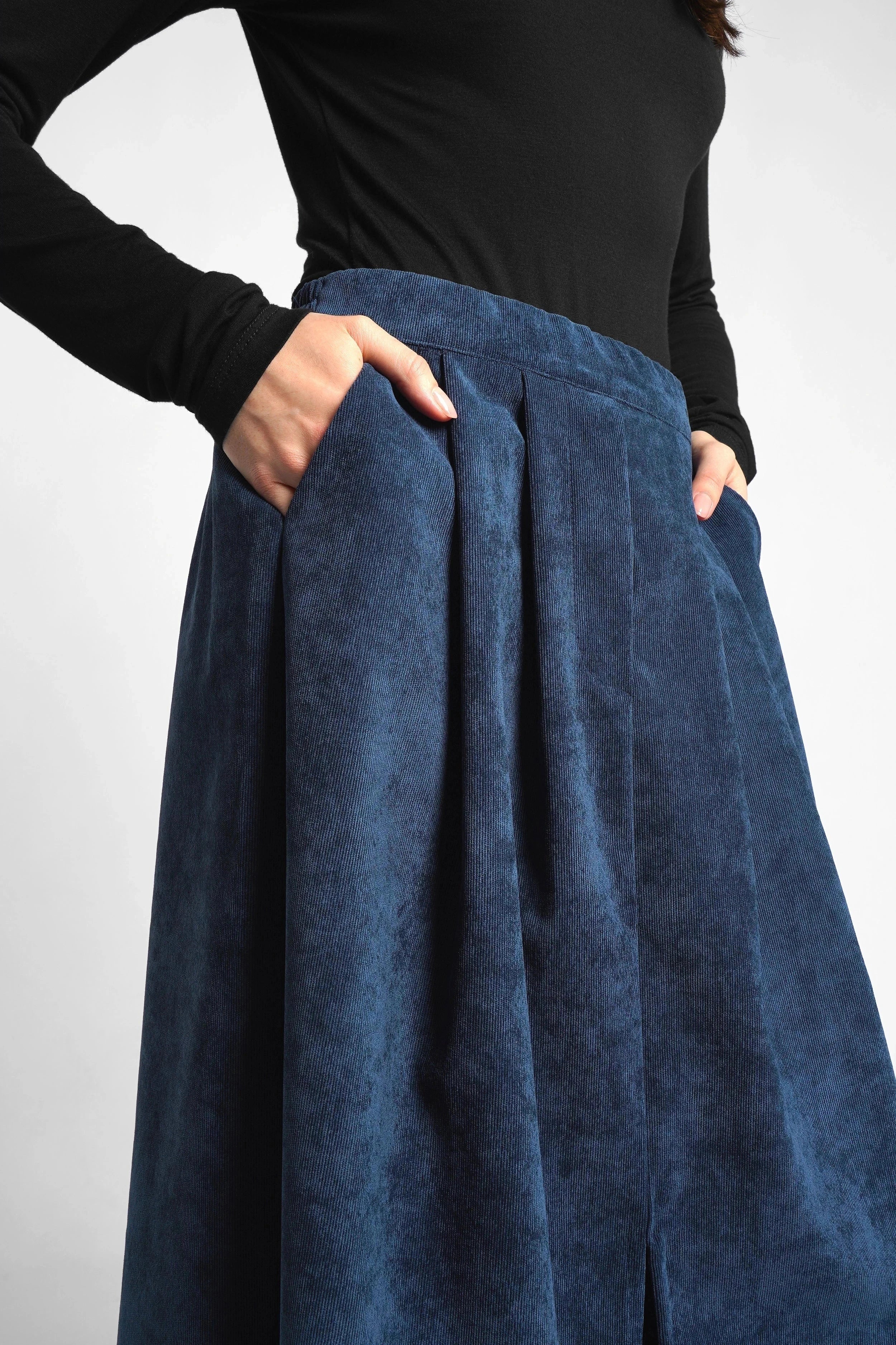 Blue corduroy midi skirt in A-line with front slits and side pockets, elastic waistband, and pleats.