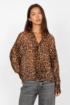 Woman wearing EDITHA Seidenbluse leopard print silk blouse with relaxed fit and tie collar