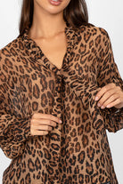 Woman wearing EDITHA Seidenbluse leopard print silk blouse with tie collar and puff sleeves.