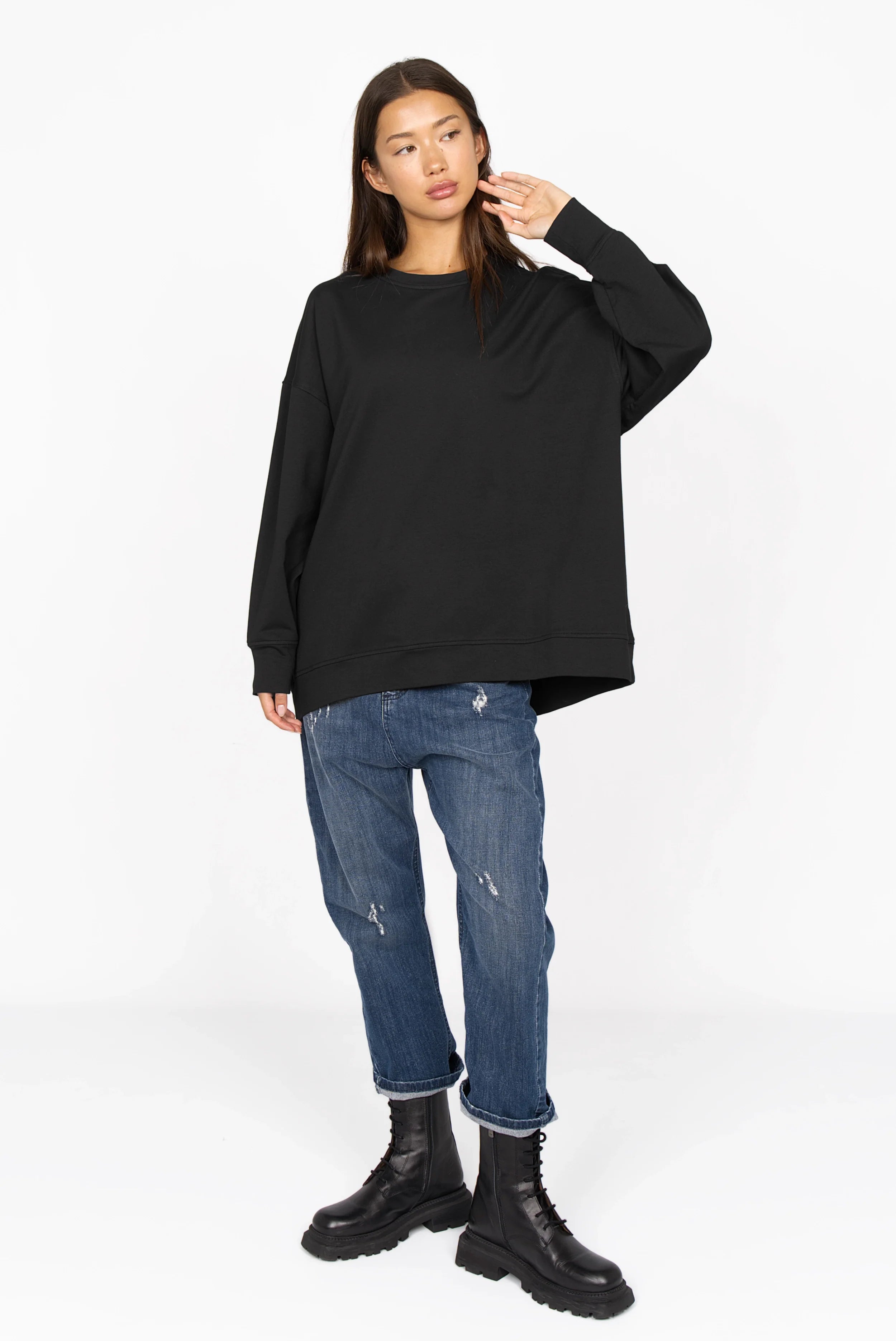 Schwarzer EIREL Oversize Sweater mit A-Linie, überschnittenen Schultern und tonaler Logo-Stickerei, kombiniert mit Jeans und schwarzen Boots