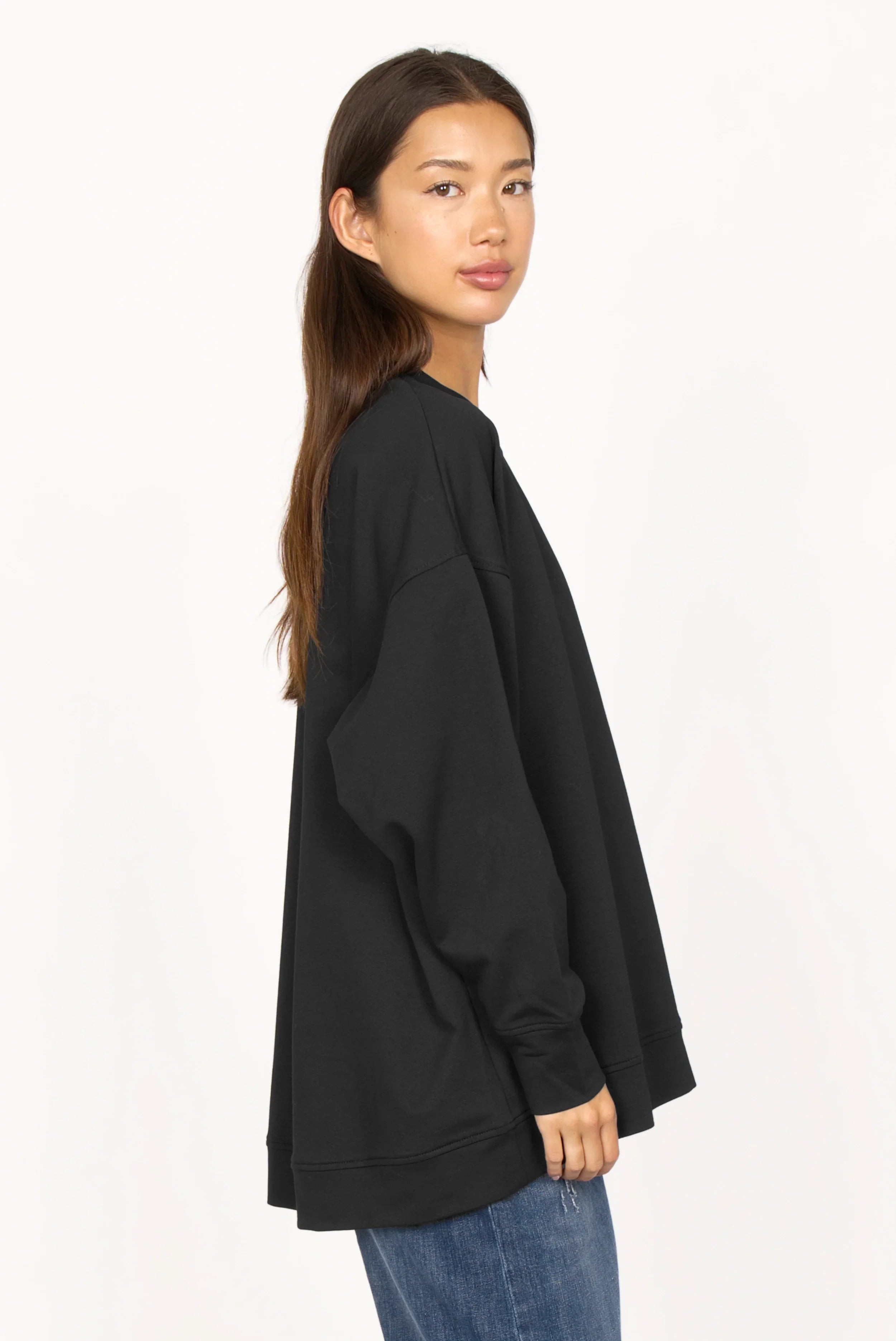 Woman wearing black EIREL oversize sweater with dropped shoulders and round neckline