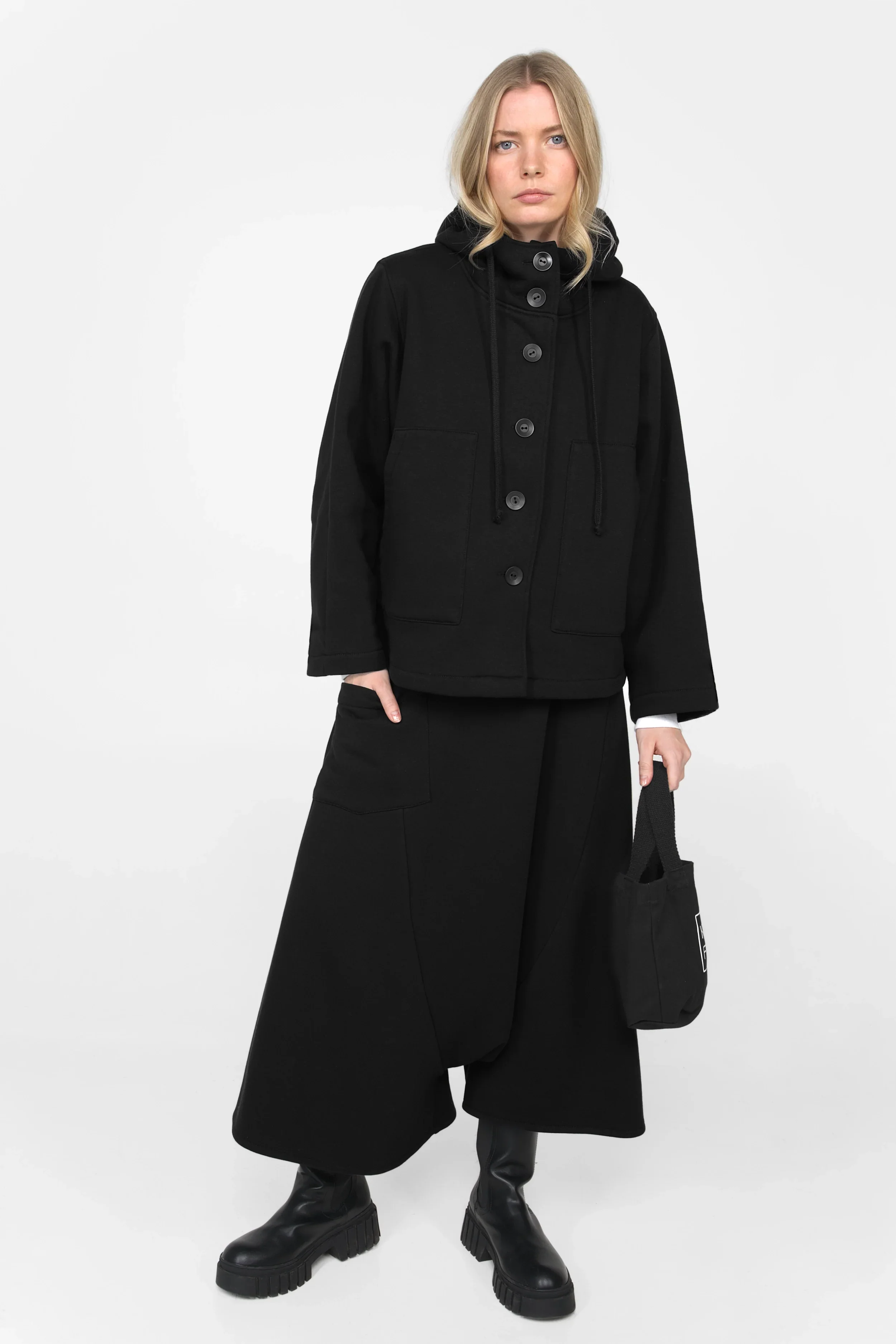 Frau trägt schwarze ELFA Sweatjacke mit Kapuze und Känguru-Taschen in Relaxed Fit