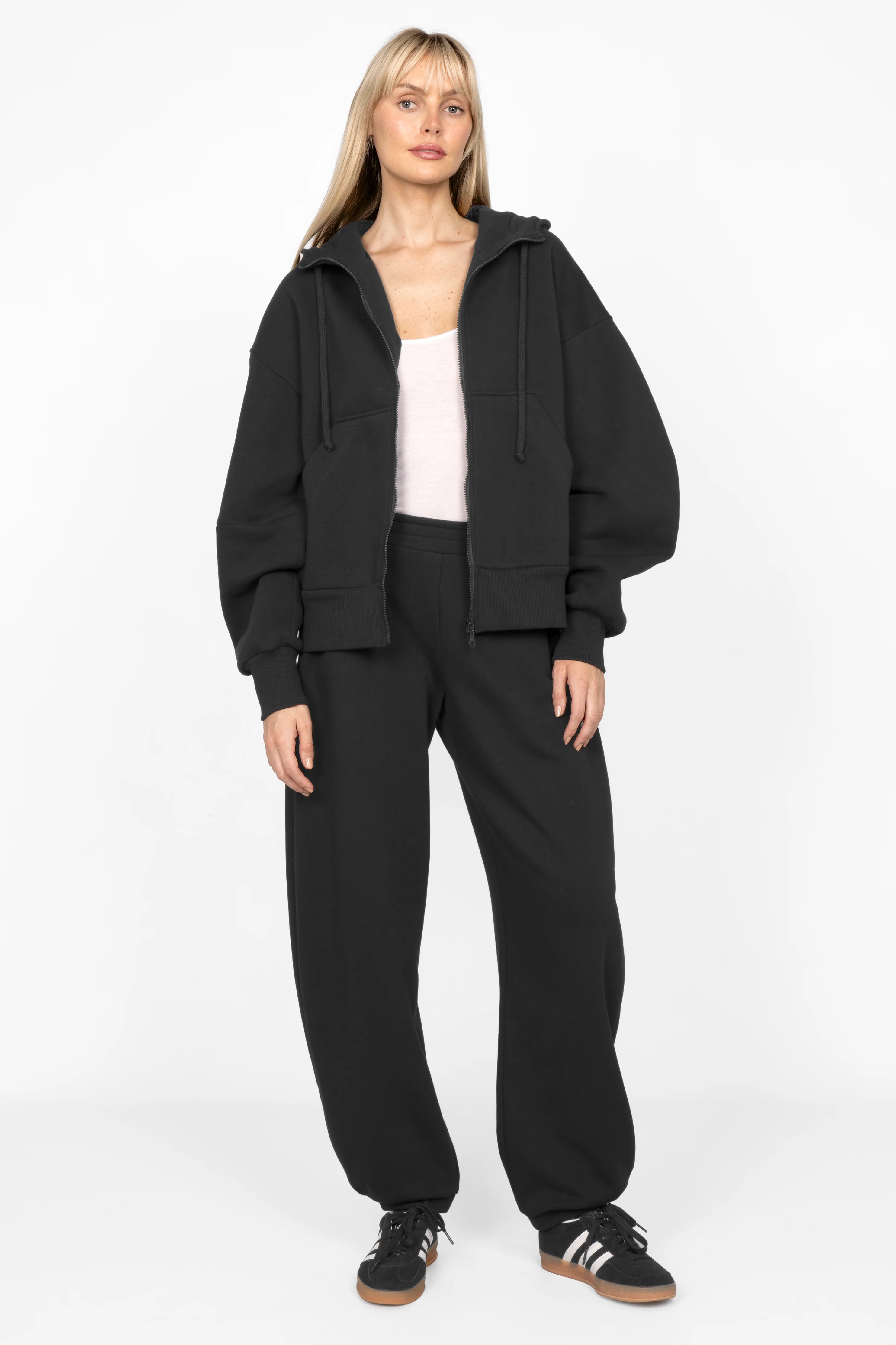 Woman wearing black ELVEA O-Shape relaxed fit sweatpants with elastic waistband and tapered legs.