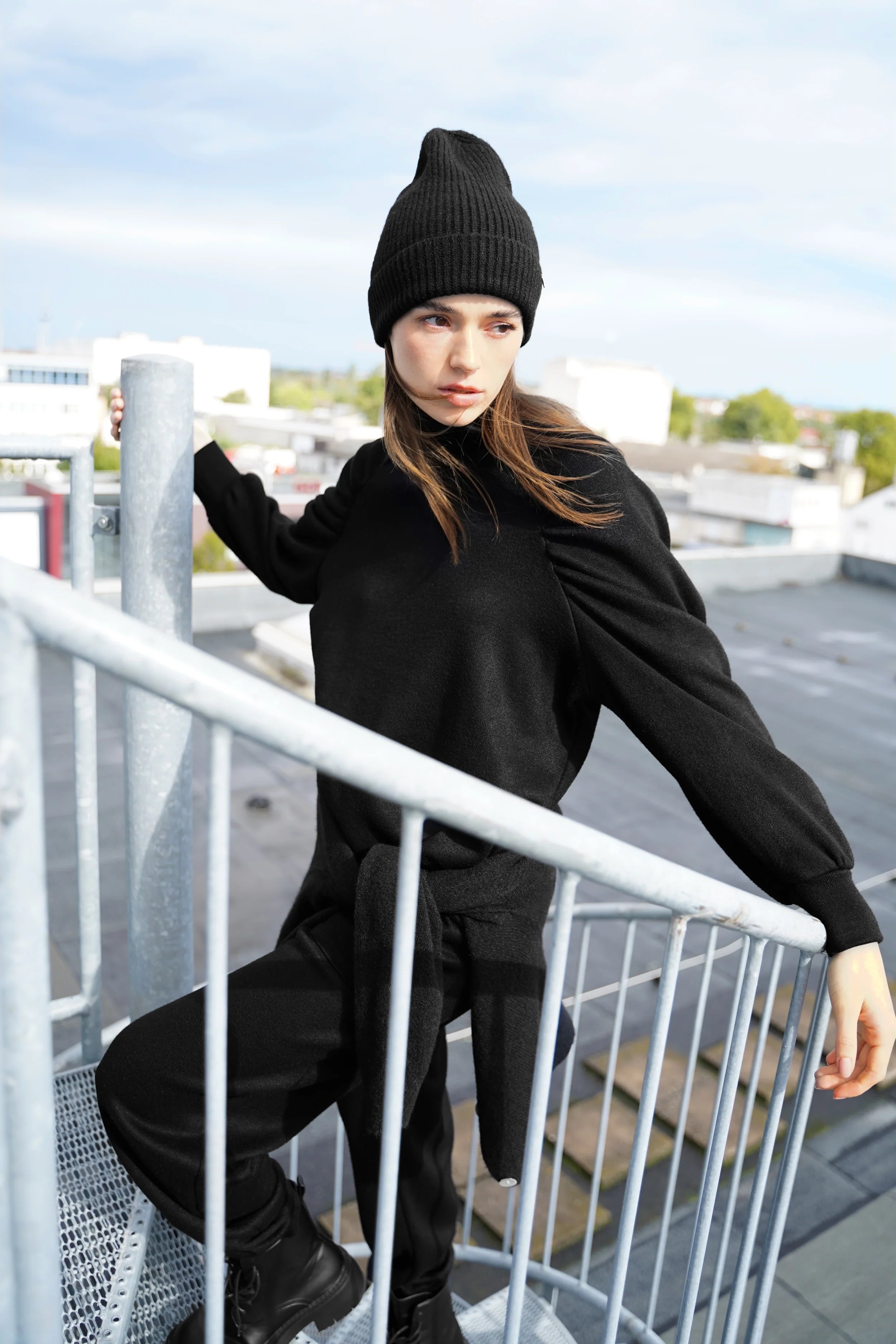 Schwarzes Oberteil aus softem Feinstrick mit Stehkragen und Raglanärmeln getragen von Frau mit Mütze