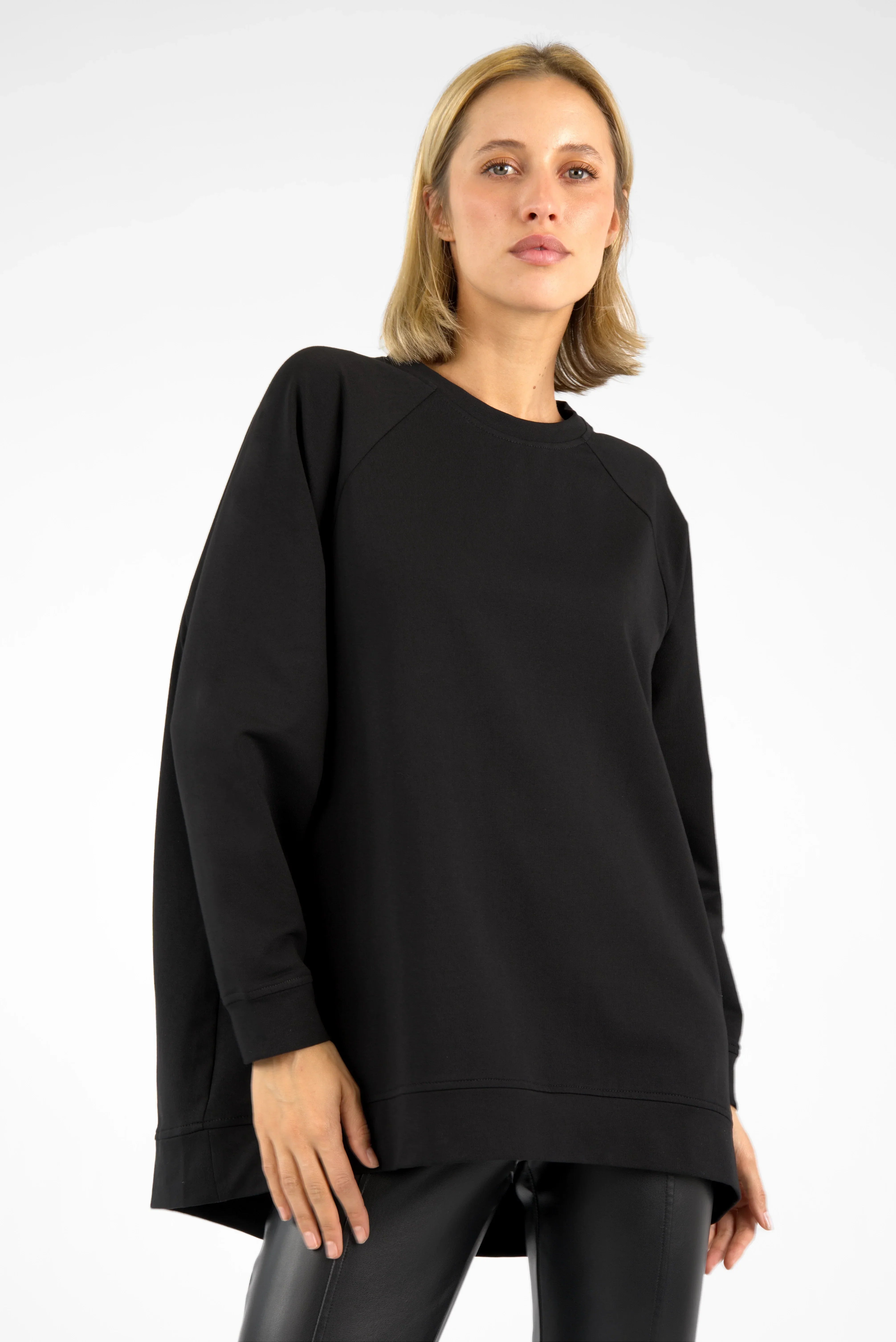 Woman wearing black GRACEY.K Sweater with A-line, raglan sleeves, and rounded hem.