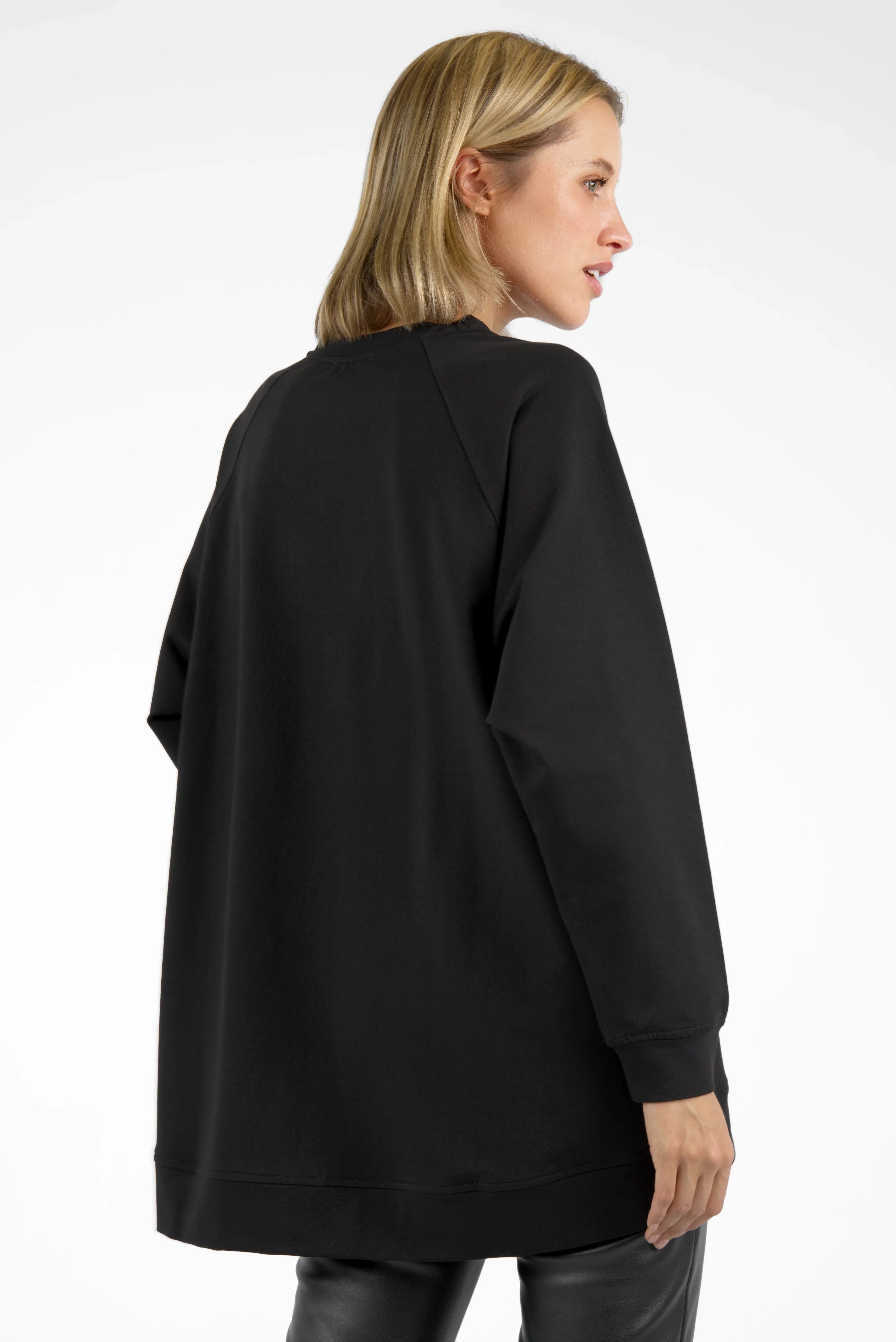 Woman wearing black GRACEY.K Sweater with raglan sleeves and extended back hem