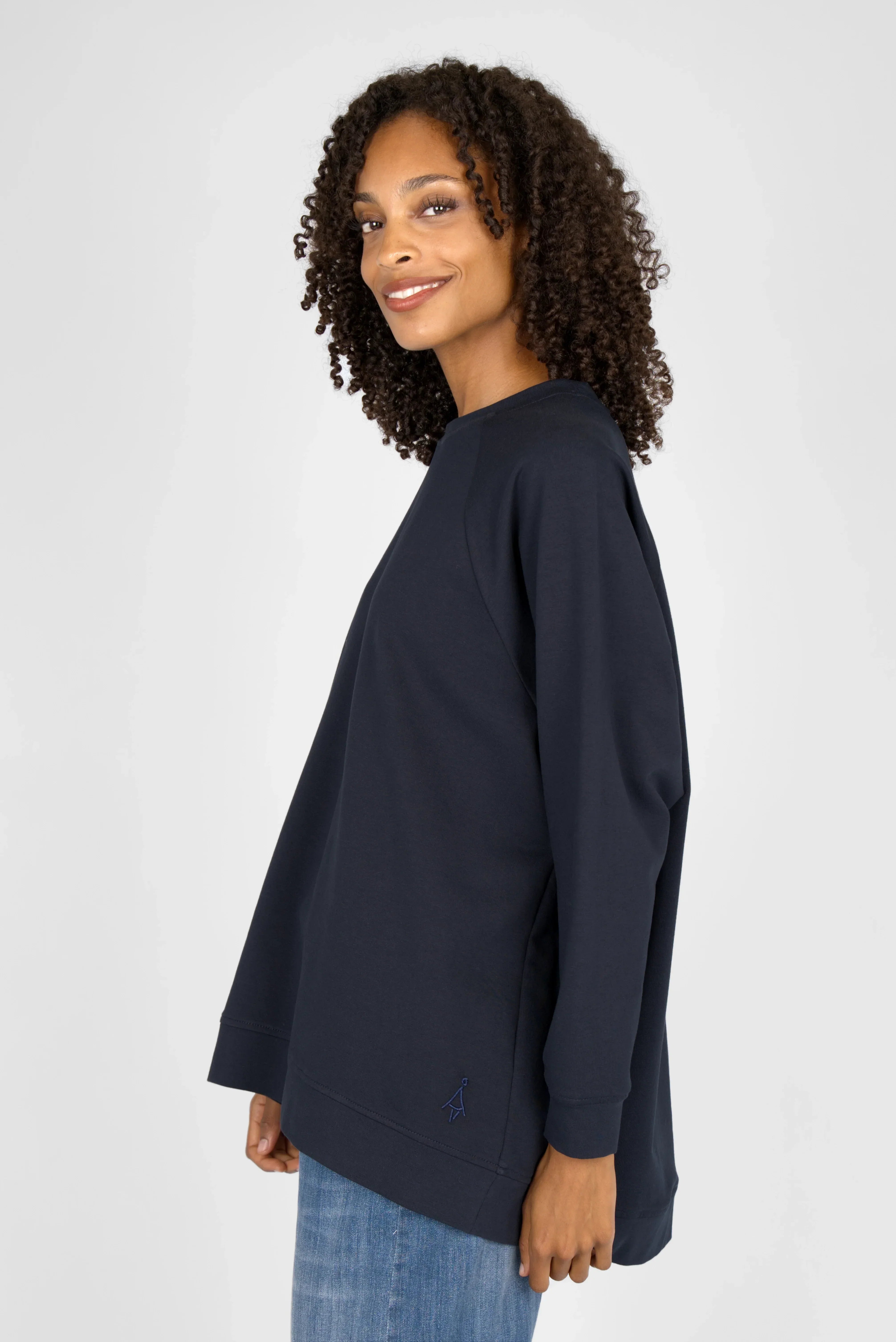 Woman wearing navy blue GRACEY.K Sweater with A-line, raglan sleeves, and tonal logo embroidery