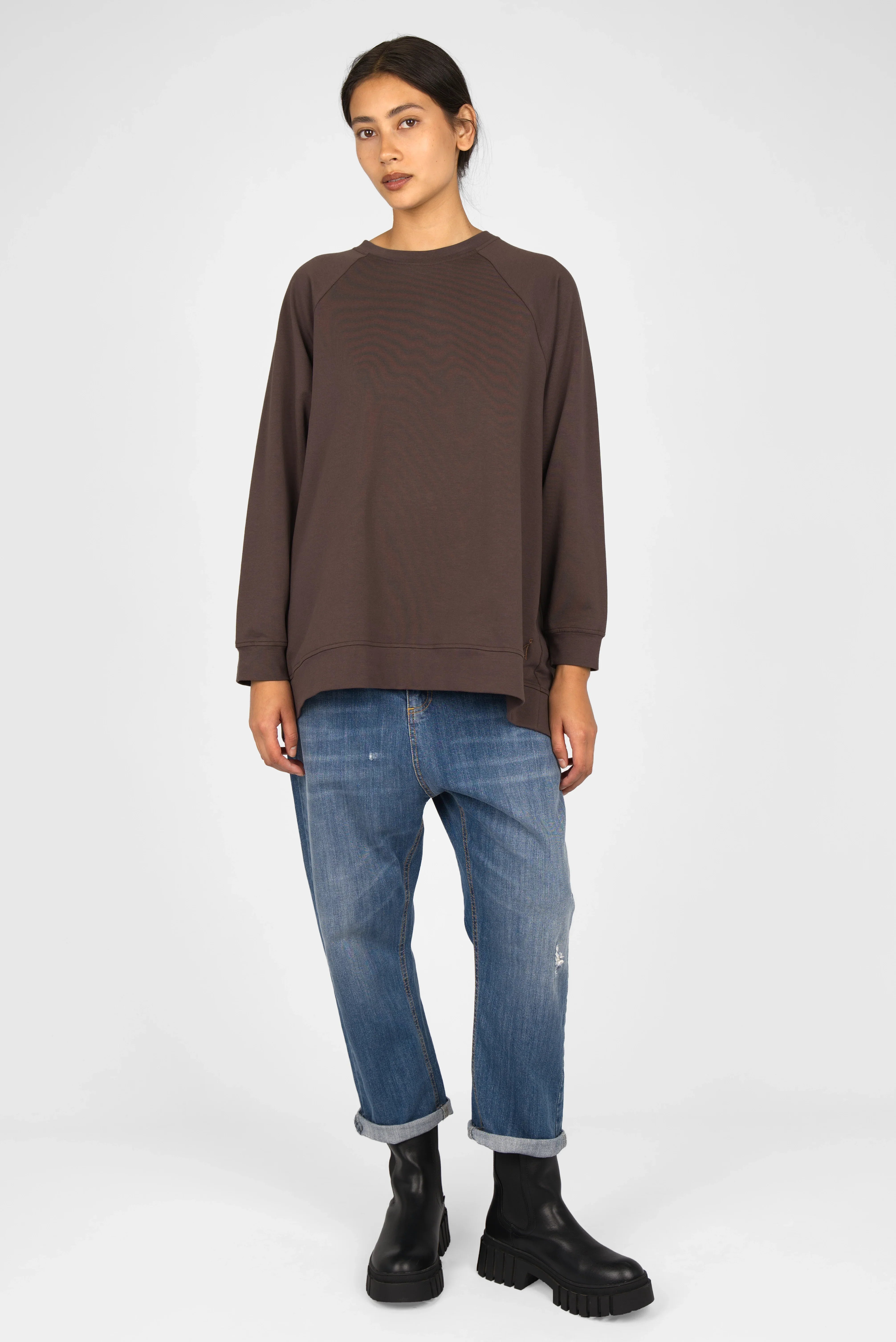Woman wearing brown GRACEY.K Sweater with A-line and raglan sleeves paired with blue jeans and black boots