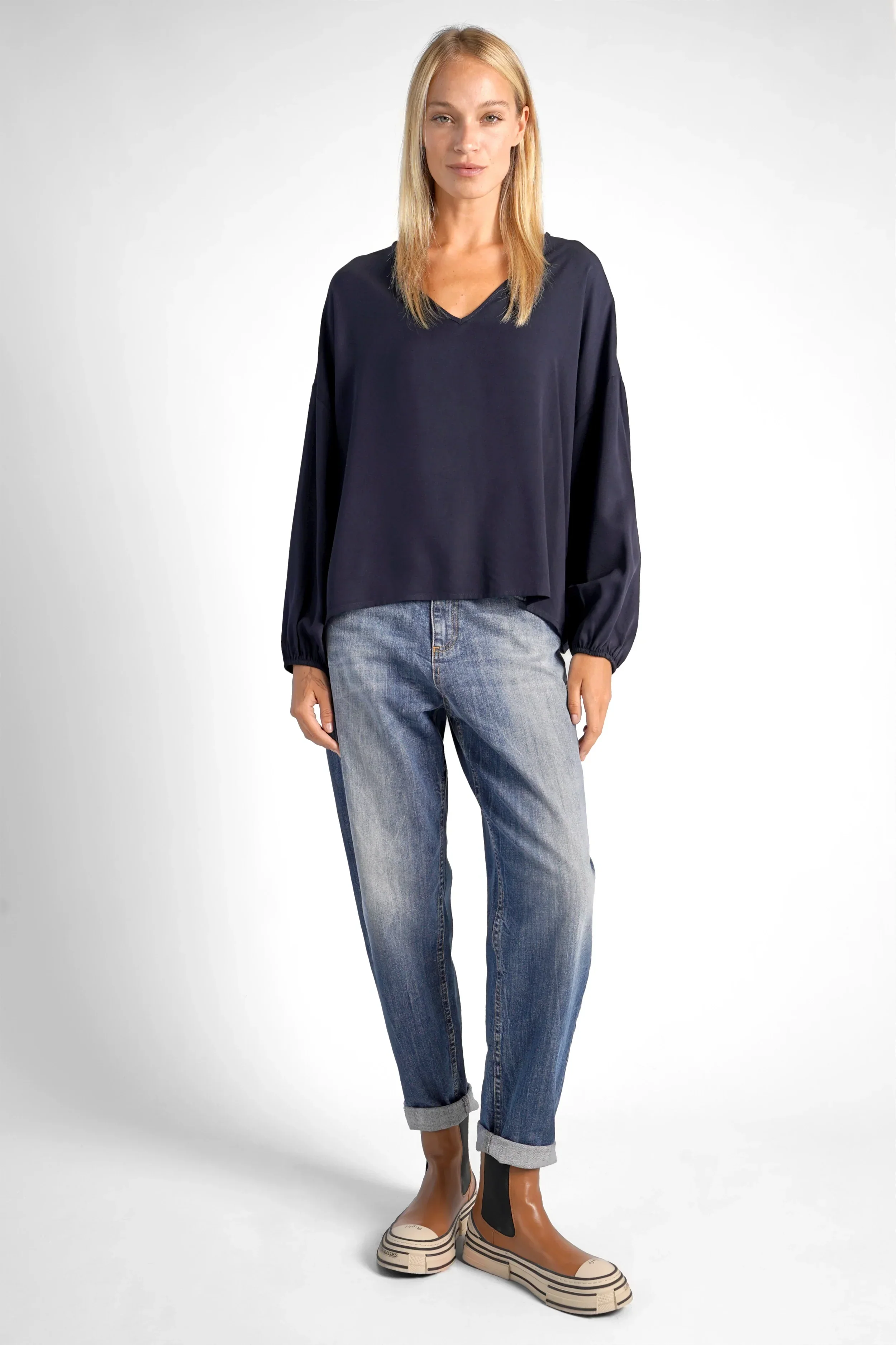 Damen GRETA.K V-Neck Bluse aus leichter Viskose mit V-Ausschnitt und Ballonärmeln, kombiniert zu Jeans und Schuhen.