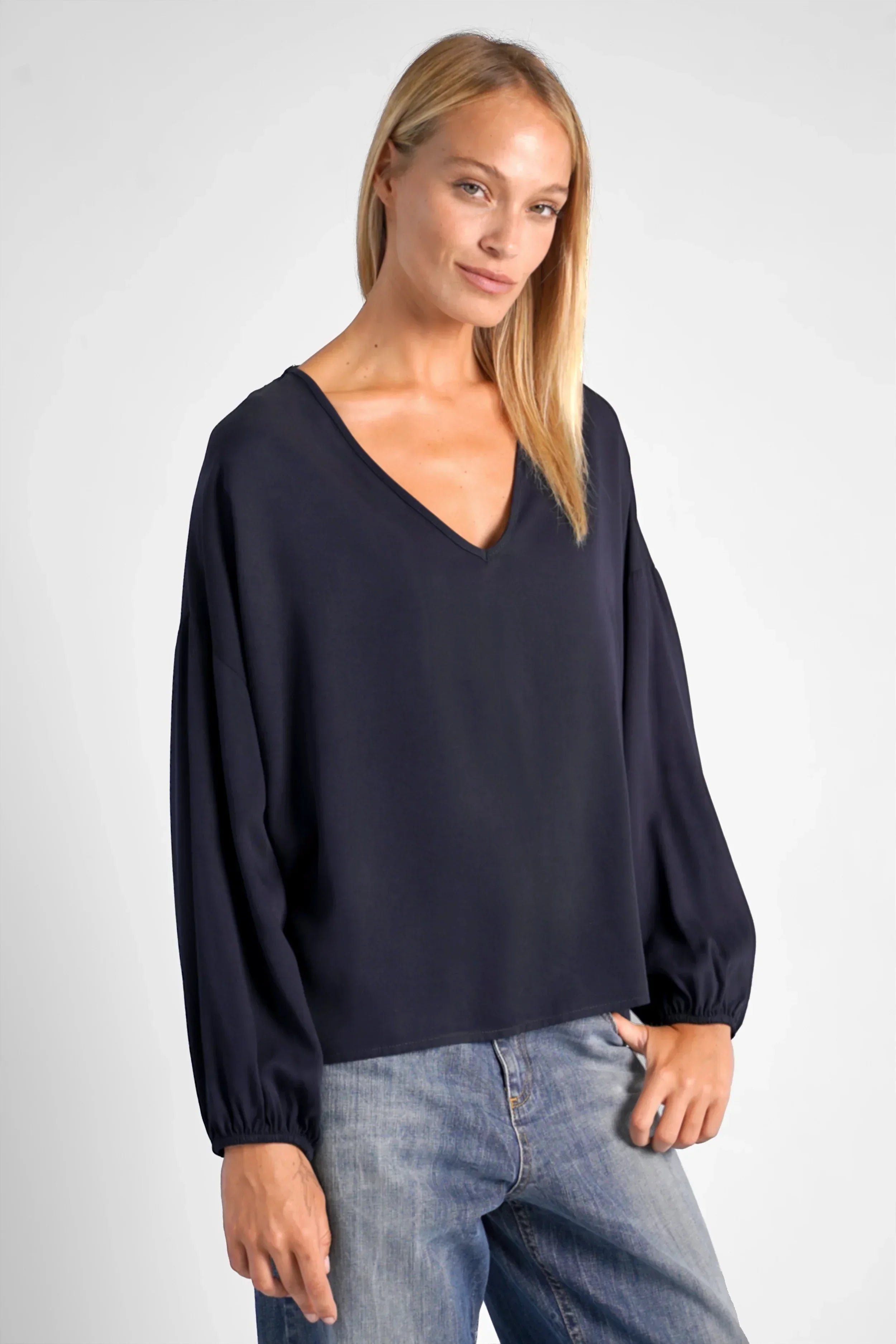 Frau trägt GRETA.K V-Neck Bluse in lockerem Schnitt mit V-Ausschnitt und langen Ärmeln aus feiner Twill Viskose