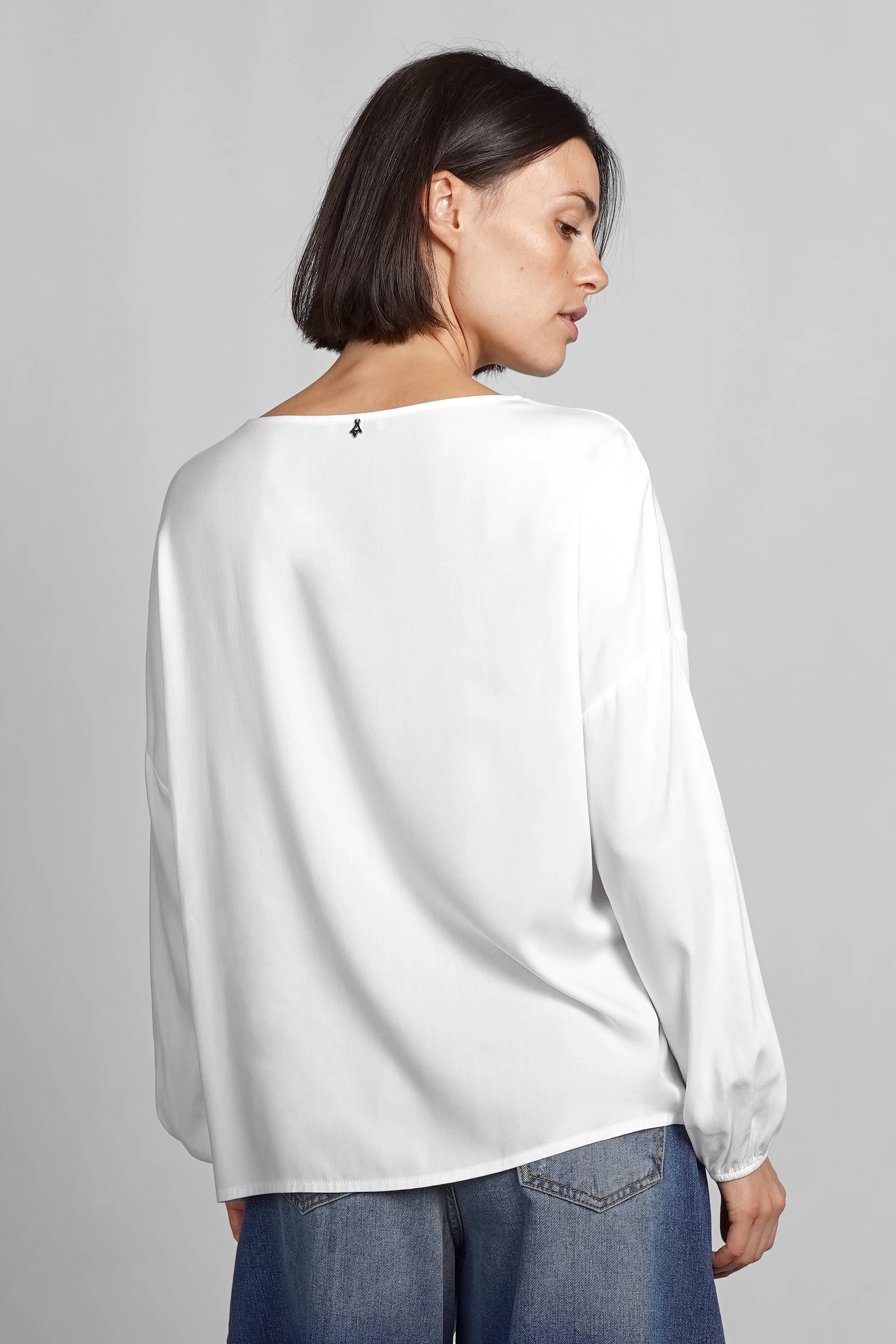 Frau trägt weiße GRETA.K Bluse aus Twill Viskose mit überschnittenen Schultern und langen Ärmeln