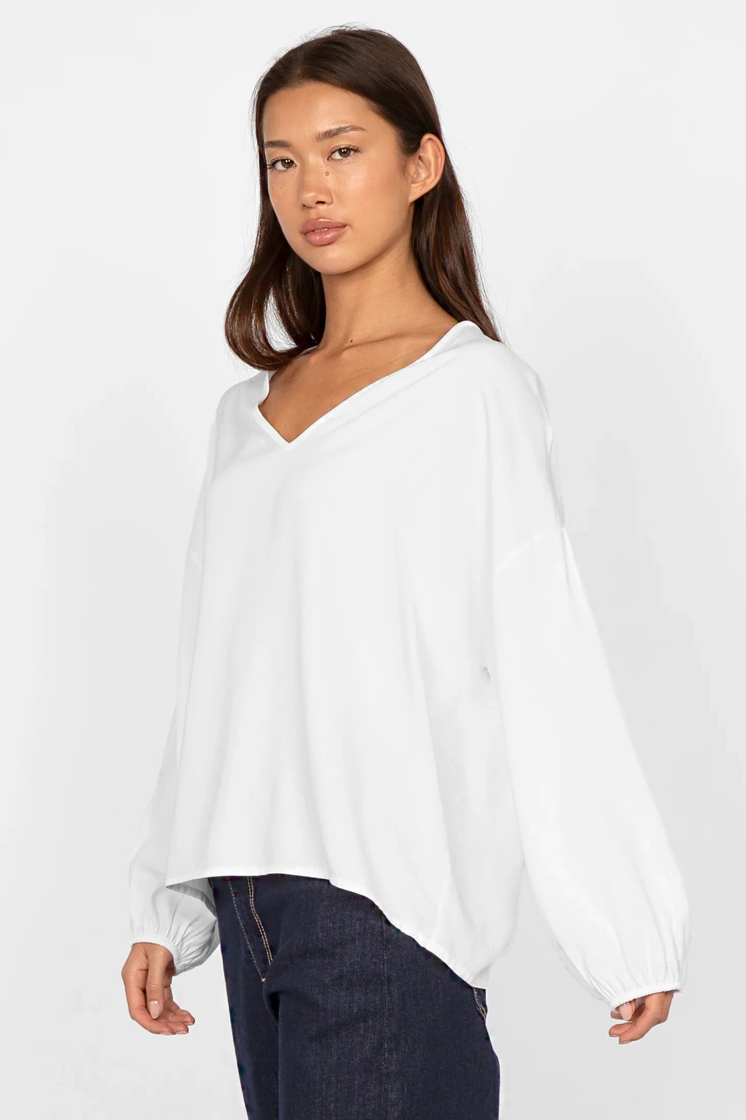 Woman wearing white GRETA.K V-Neck Bluse with relaxed fit and long sleeves against plain background