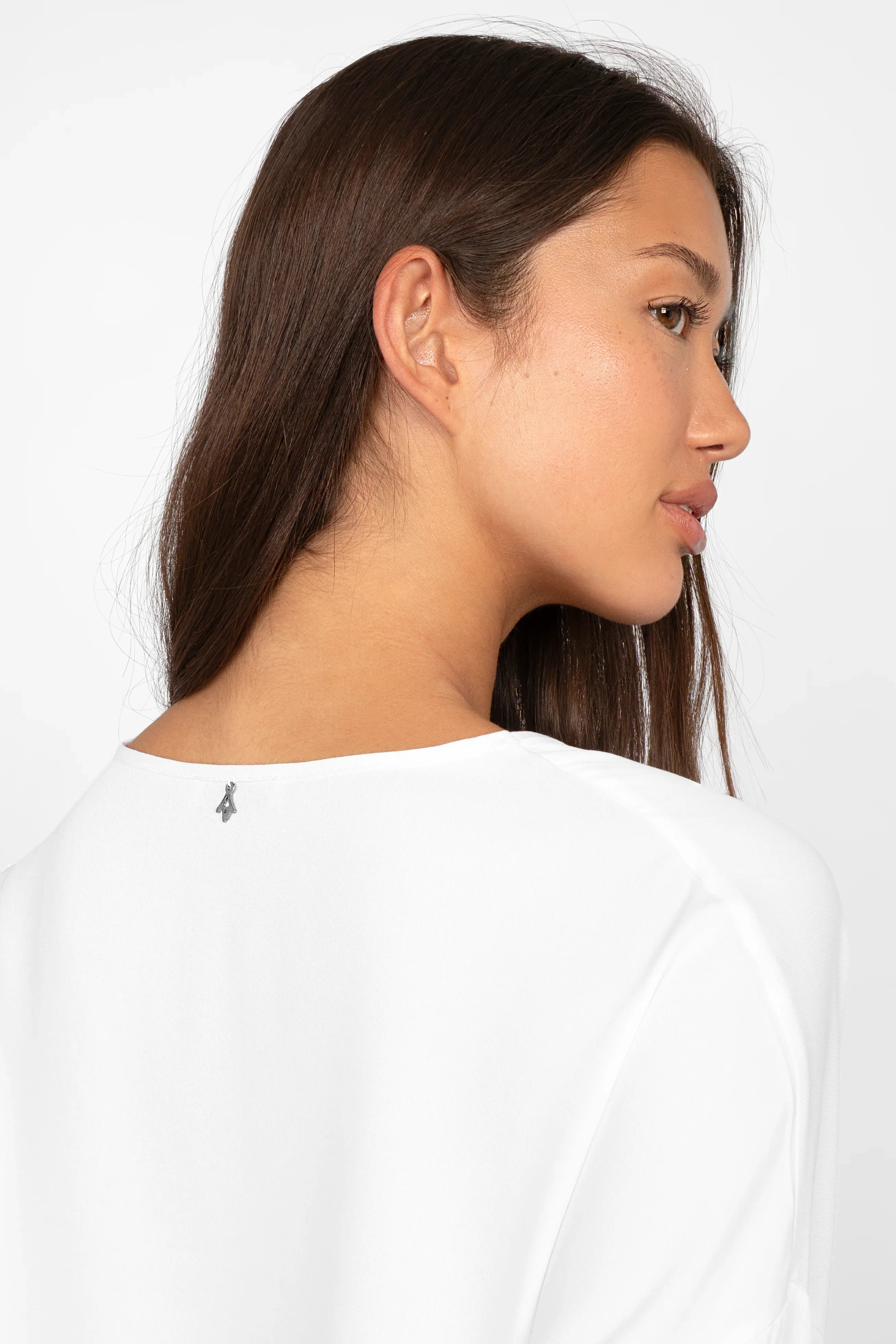 Frau trägt weiße GRETA.K V-Neck Bluse mit überschnittenen Schultern und elastischen Ärmelabschlüssen, Rückansicht