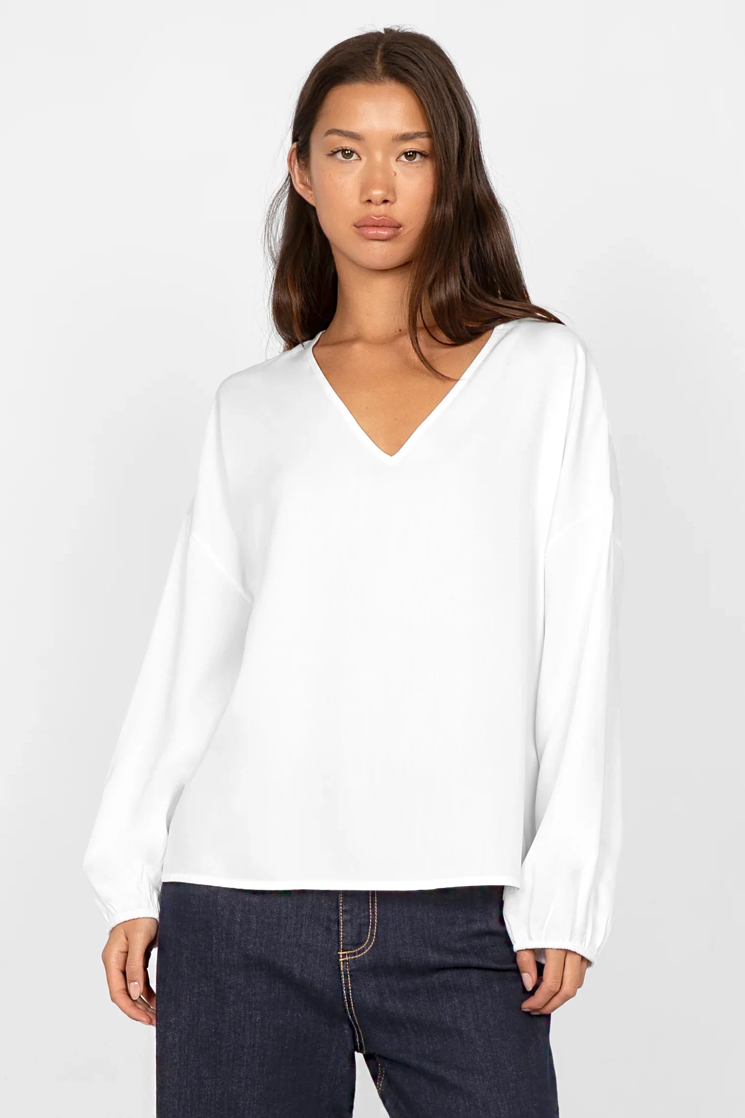 Weiße GRETA.K V-Neck Bluse aus weicher Twill Viskose mit lockerem Schnitt, V-Ausschnitt und langen Ärmeln mit elastischen Abschlüssen.