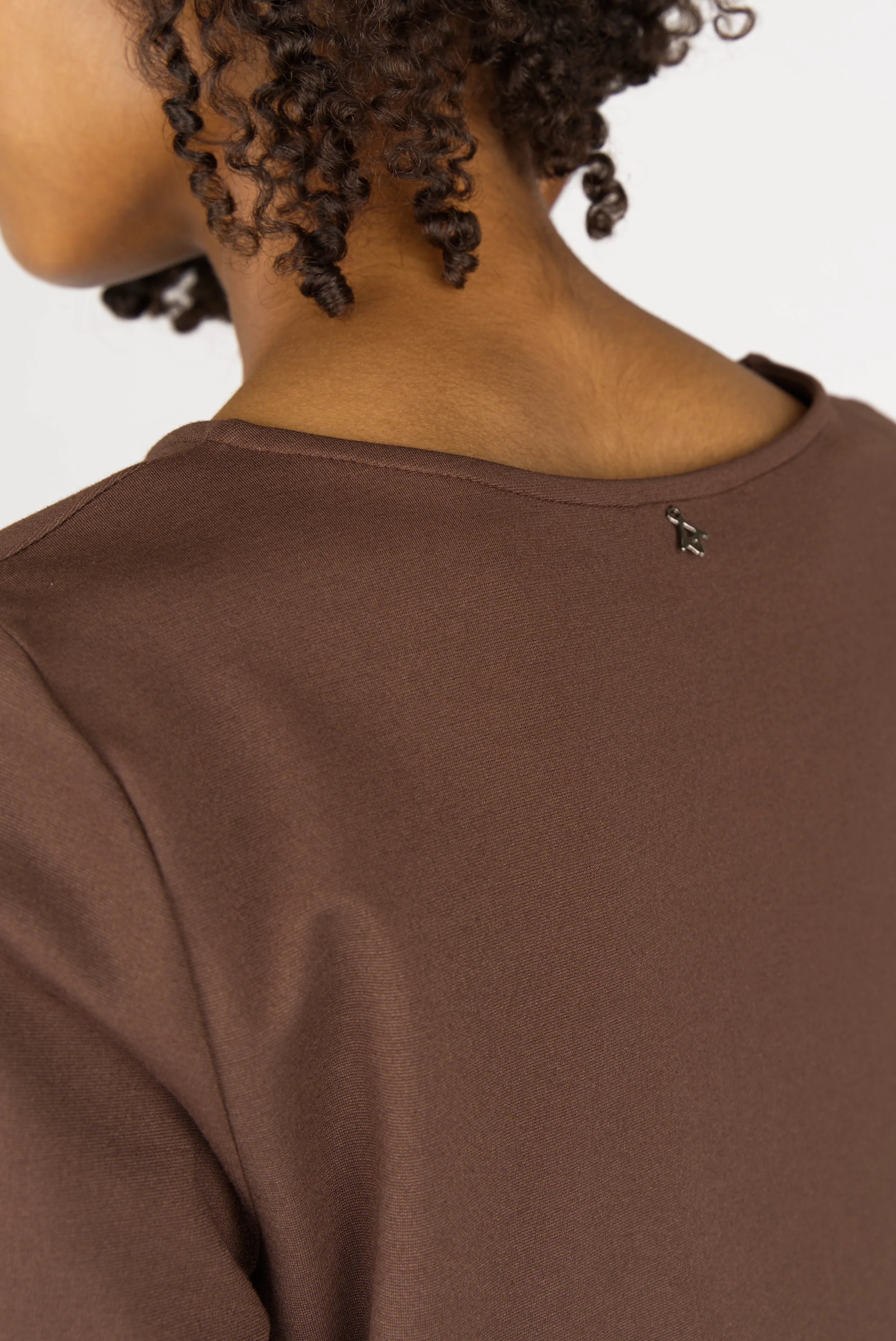 Close-up of brown HAEIN Clean Jersey long sleeve top with U-boat neckline and smooth viscose fabric on model's shoulder and back.