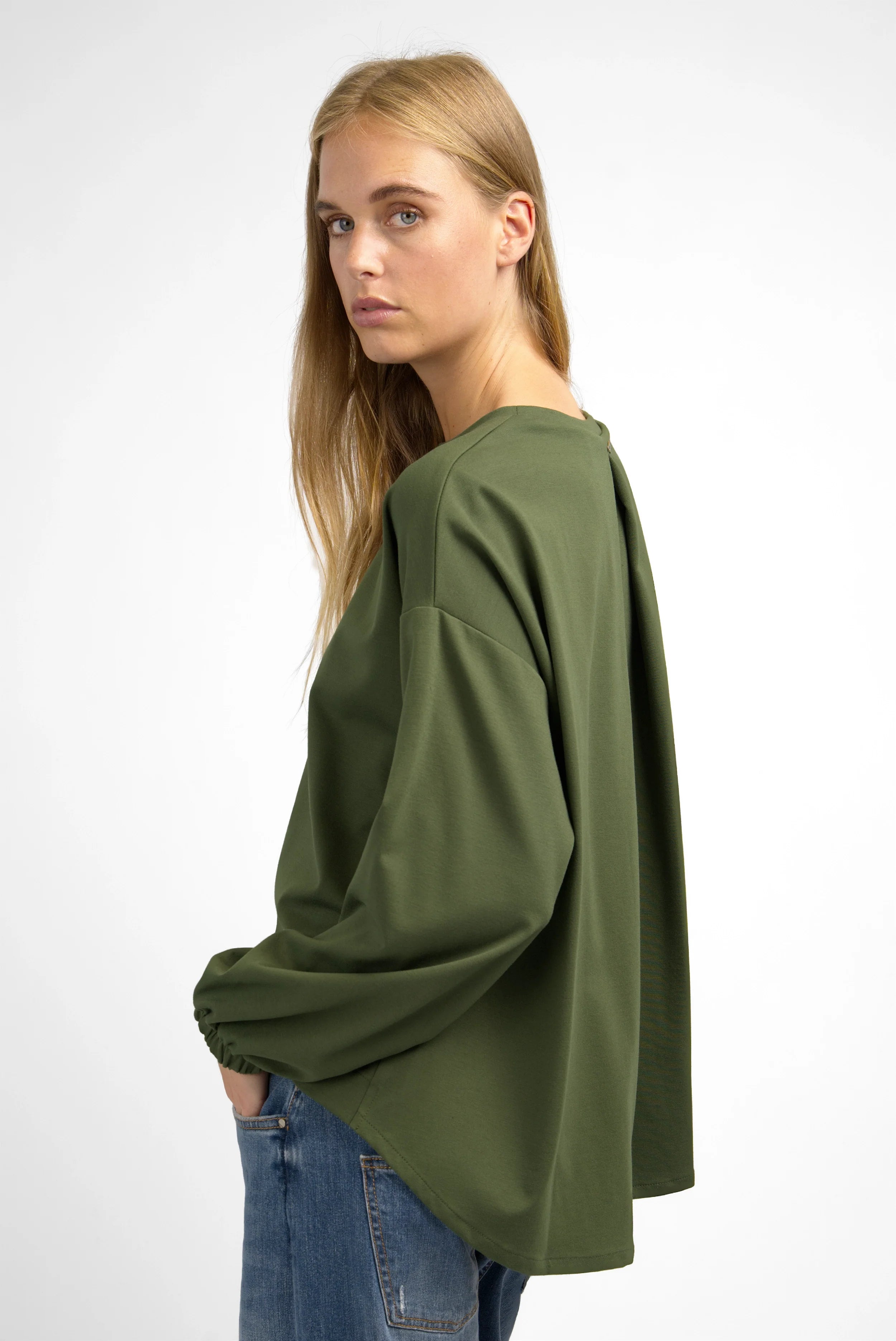 Damen trägt lockeres HAGLA Shirt aus grünem Heavy Viskose-Mix mit Rundhalsausschnitt und elastischen Ärmelbündchen